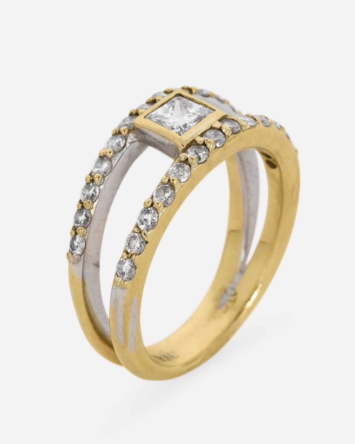 A yellow and white gold double band with pave diamonds and a center princess cut diamond. Shown standing up from the side.