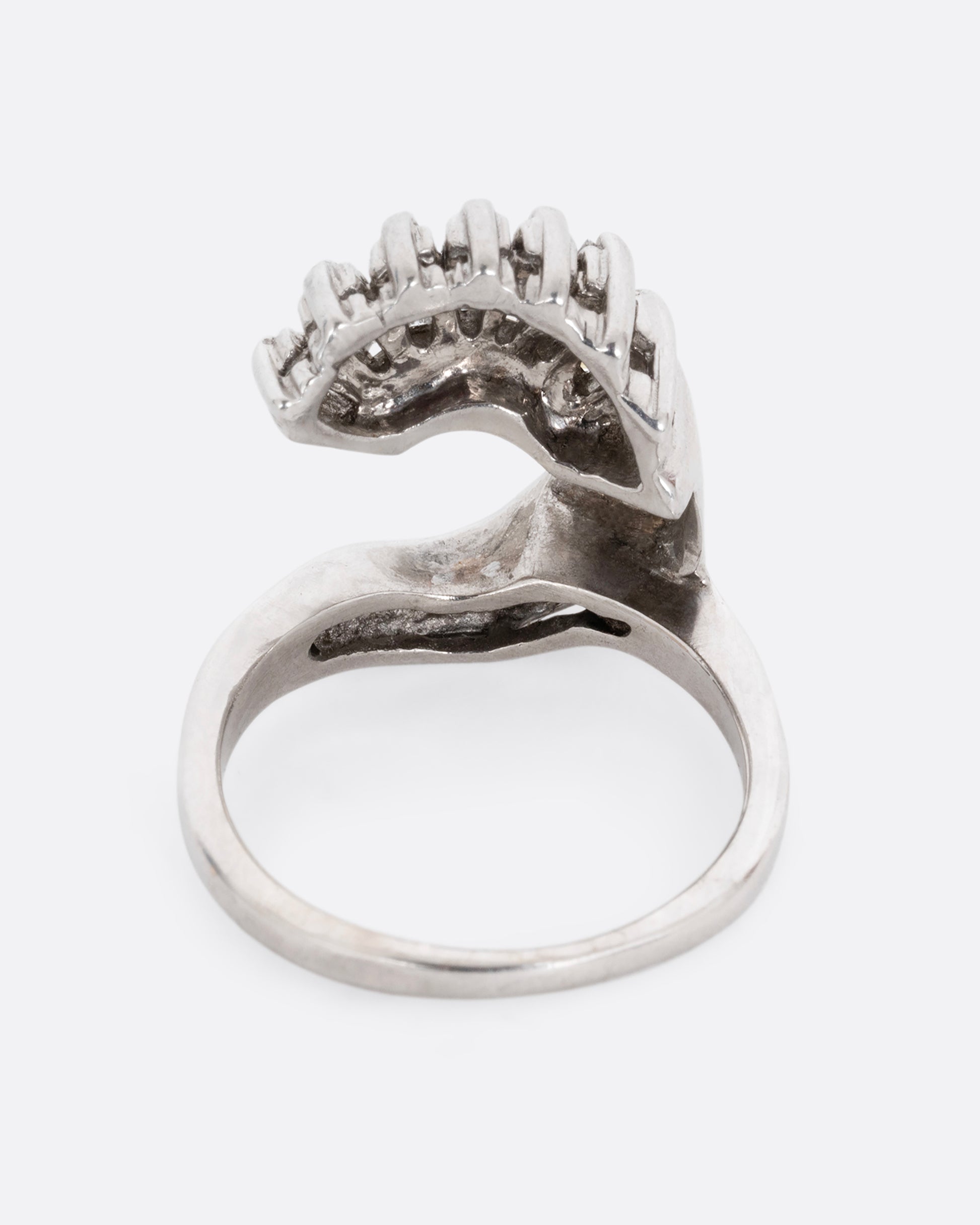 A white gold wave ring with baguette diamonds and round diamonds. Shown from the back.