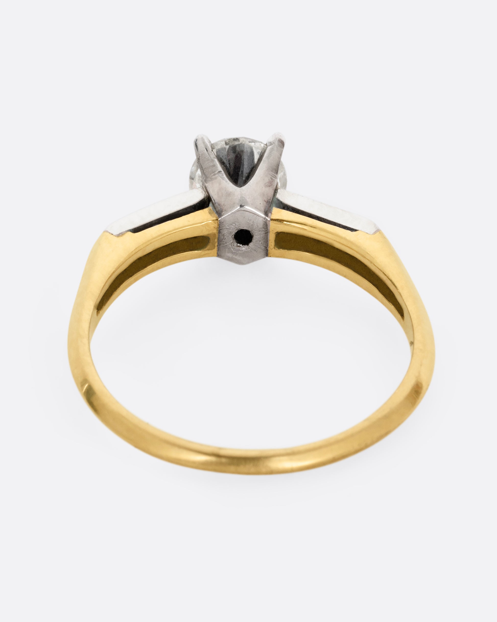 A yellow gold ring with white gold setting and six channel set diamonds with a central prong set brilliant cut diamond. Shown from the back.