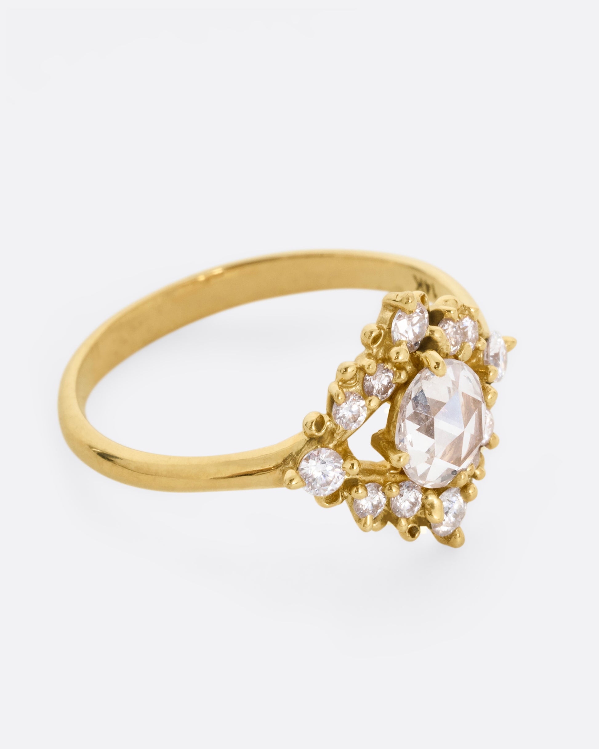 A yellow gold ring with a rose cut center diamond surrounded by round diamonds. Shown from the side.