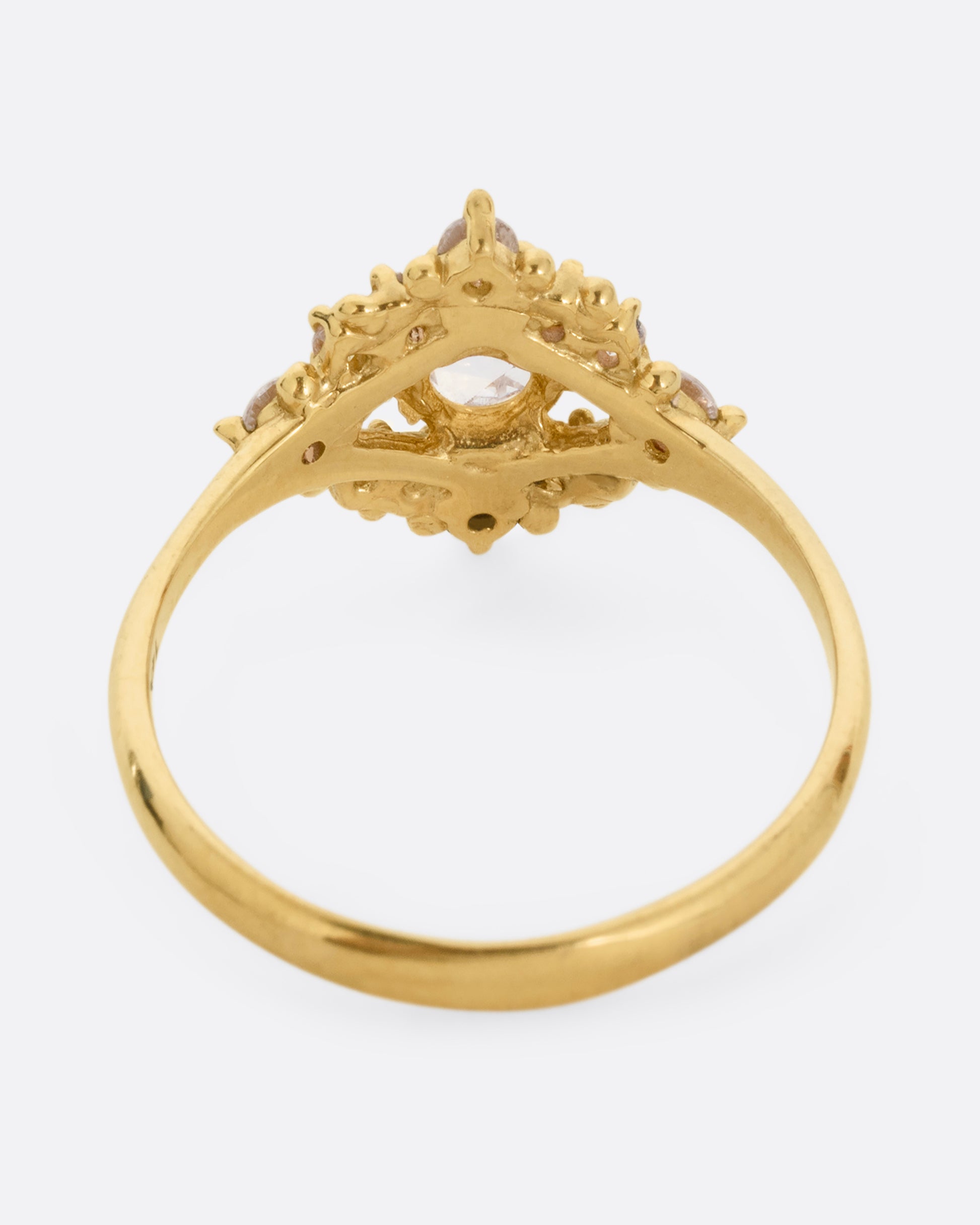A yellow gold ring with a rose cut center diamond surrounded by round diamonds. Shown from the back.