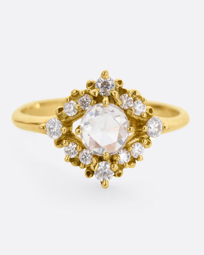 A yellow gold ring with a rose cut center diamond surrounded by round diamonds. Shown from the front.