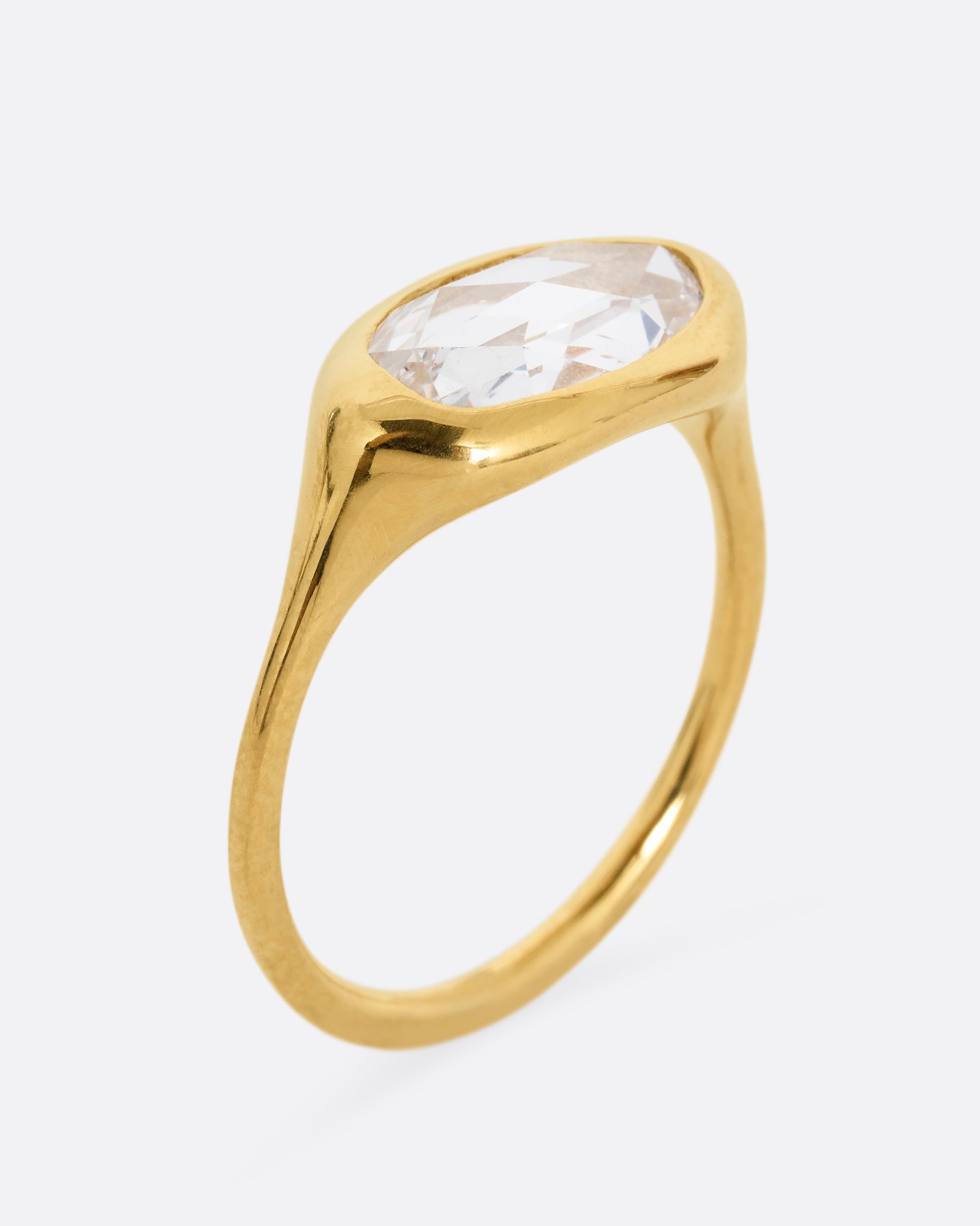 A yellow gold ring with a n oval rose cut diamond. Shown standing up from the side.