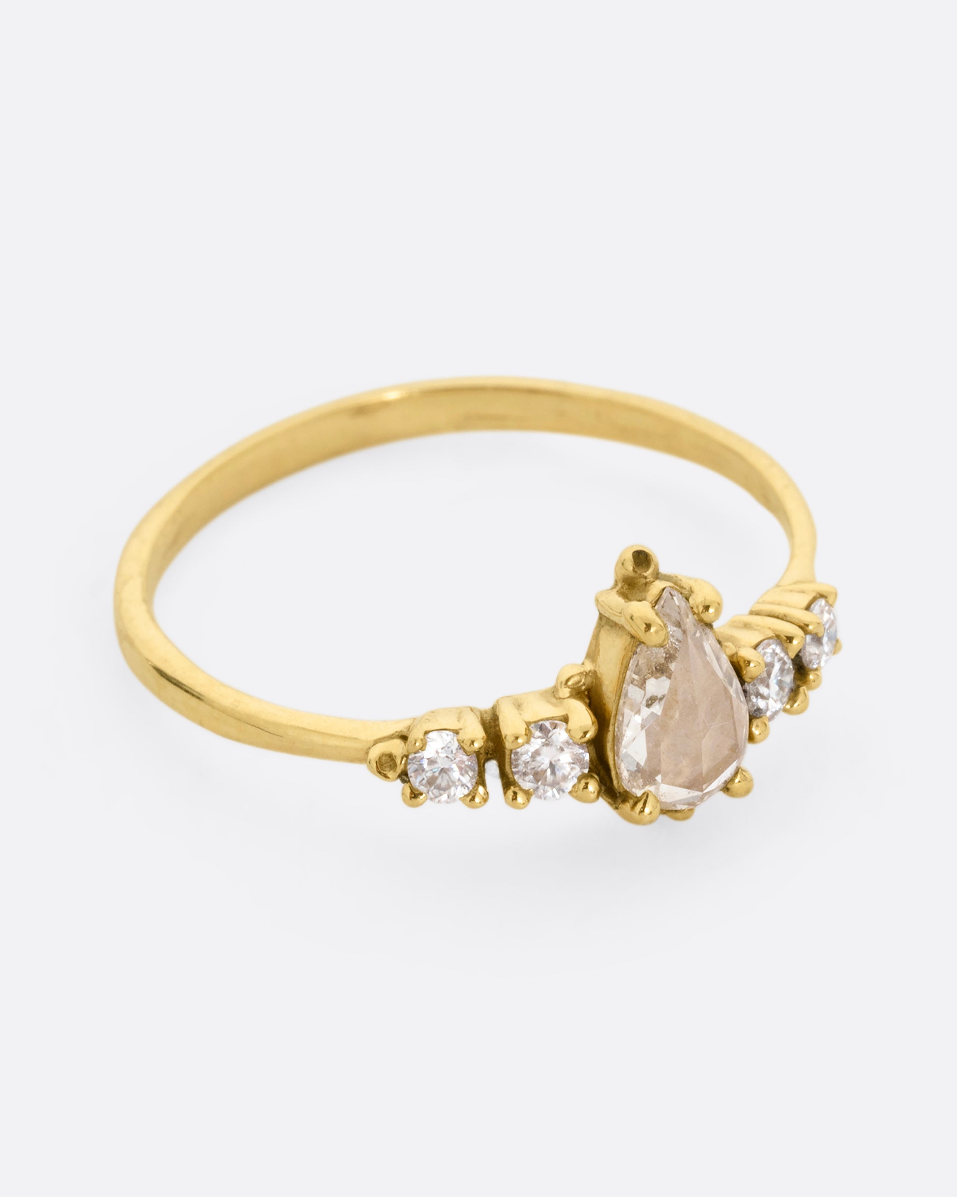  A yellow gold ring with a pear shaped champagne diamond with round white diamond accents. Shown from the side.