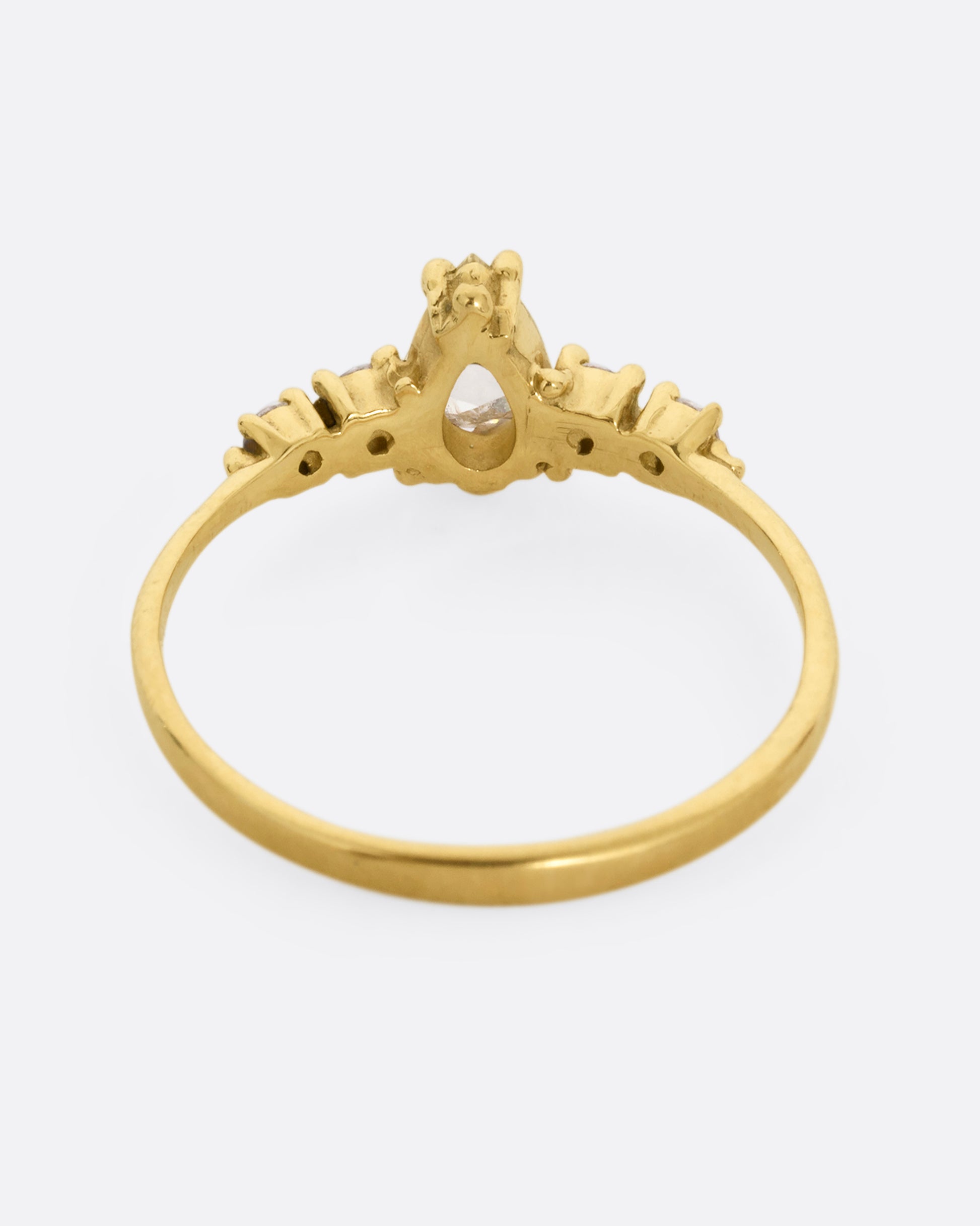  A yellow gold ring with a pear shaped champagne diamond with round white diamond accents. Shown from the back.