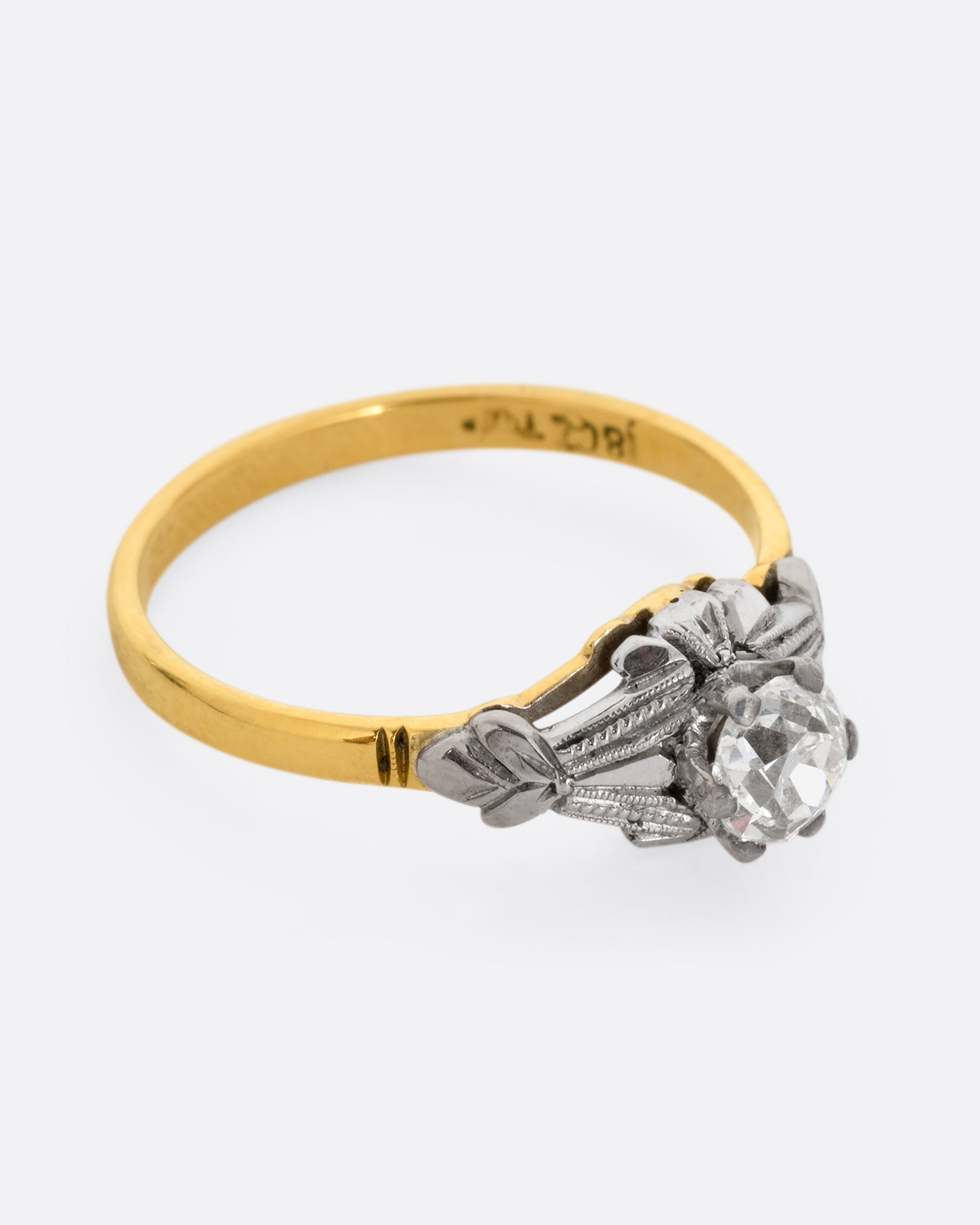 A yellow gold and platinum ring with an Old Mine Cut diamond and baguette diamonds. Shown from the side.