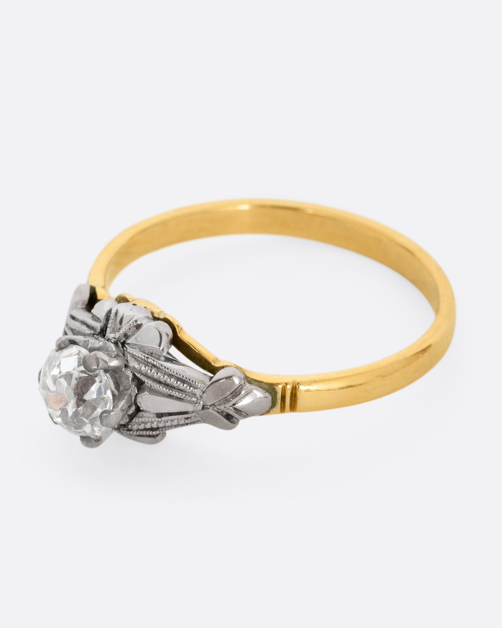 A yellow gold and platinum ring with an Old Mine Cut diamond and baguette diamonds. Shown from the side.