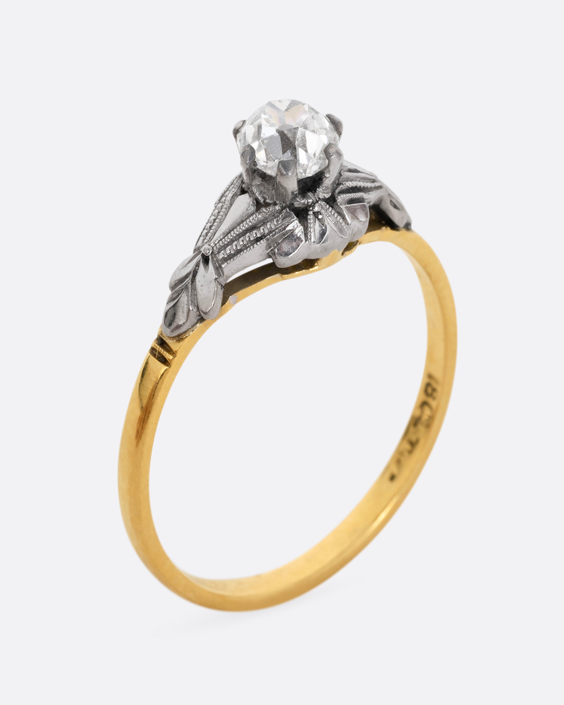 A yellow gold and platinum ring with an Old Mine Cut diamond and baguette diamonds. Shown standing up from the side.