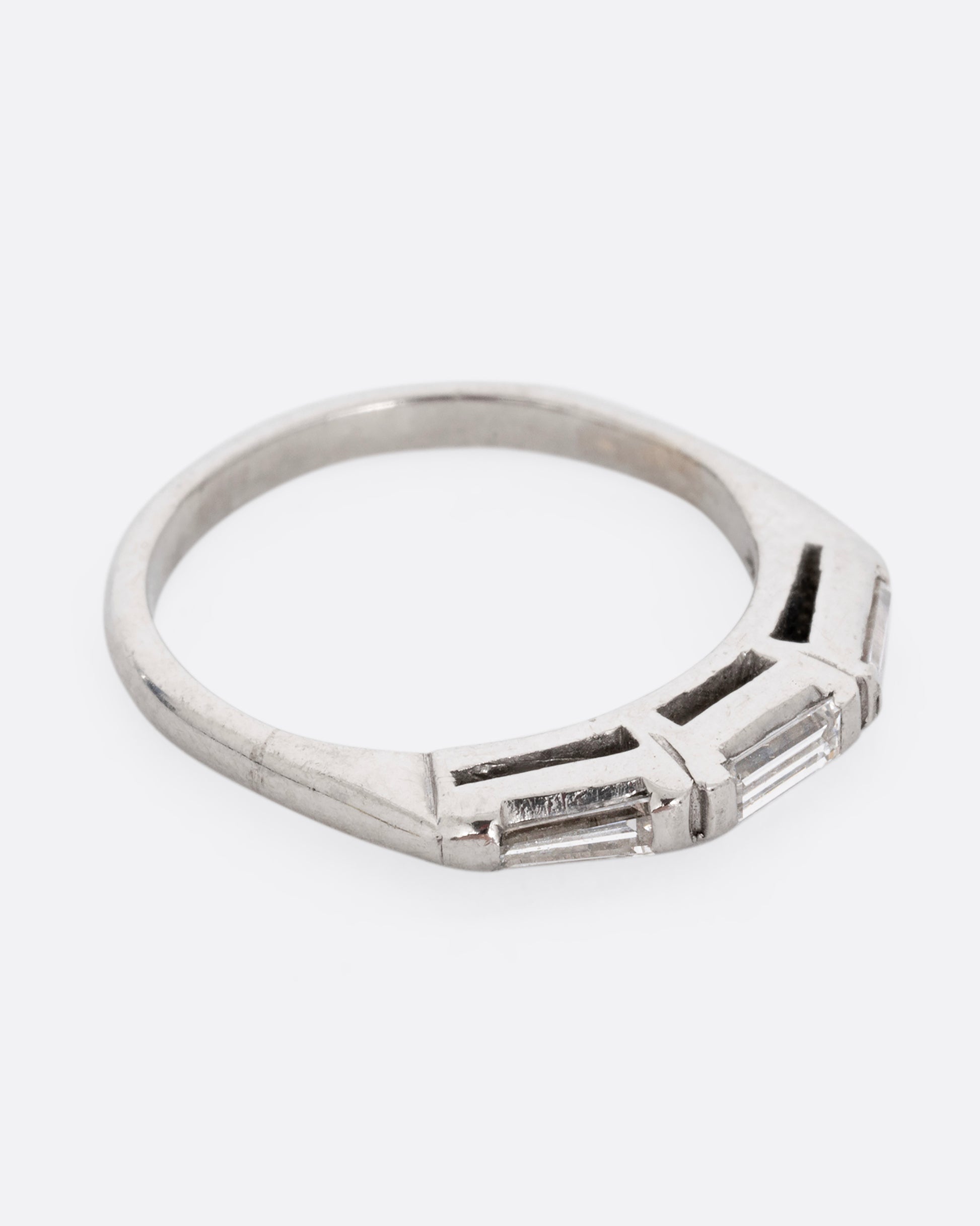 A platinum ring with three baguette diamonds. Shown from the side.