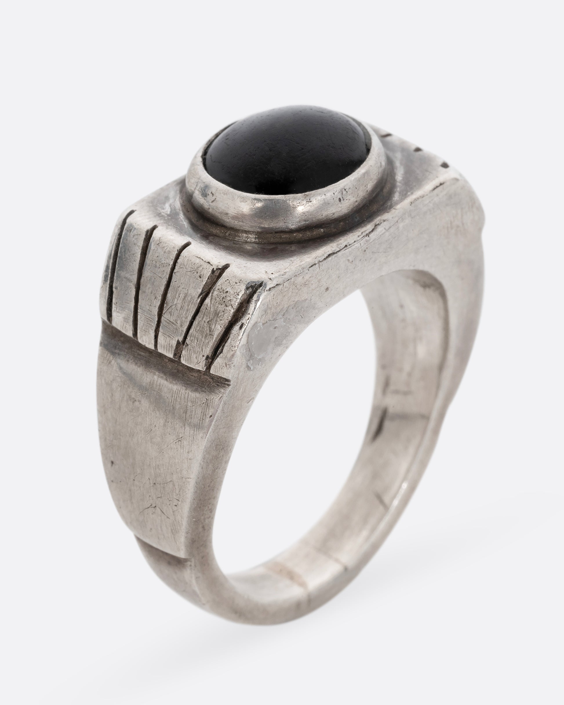 A silver ring with an oval onyx. Shown standing up from the side.