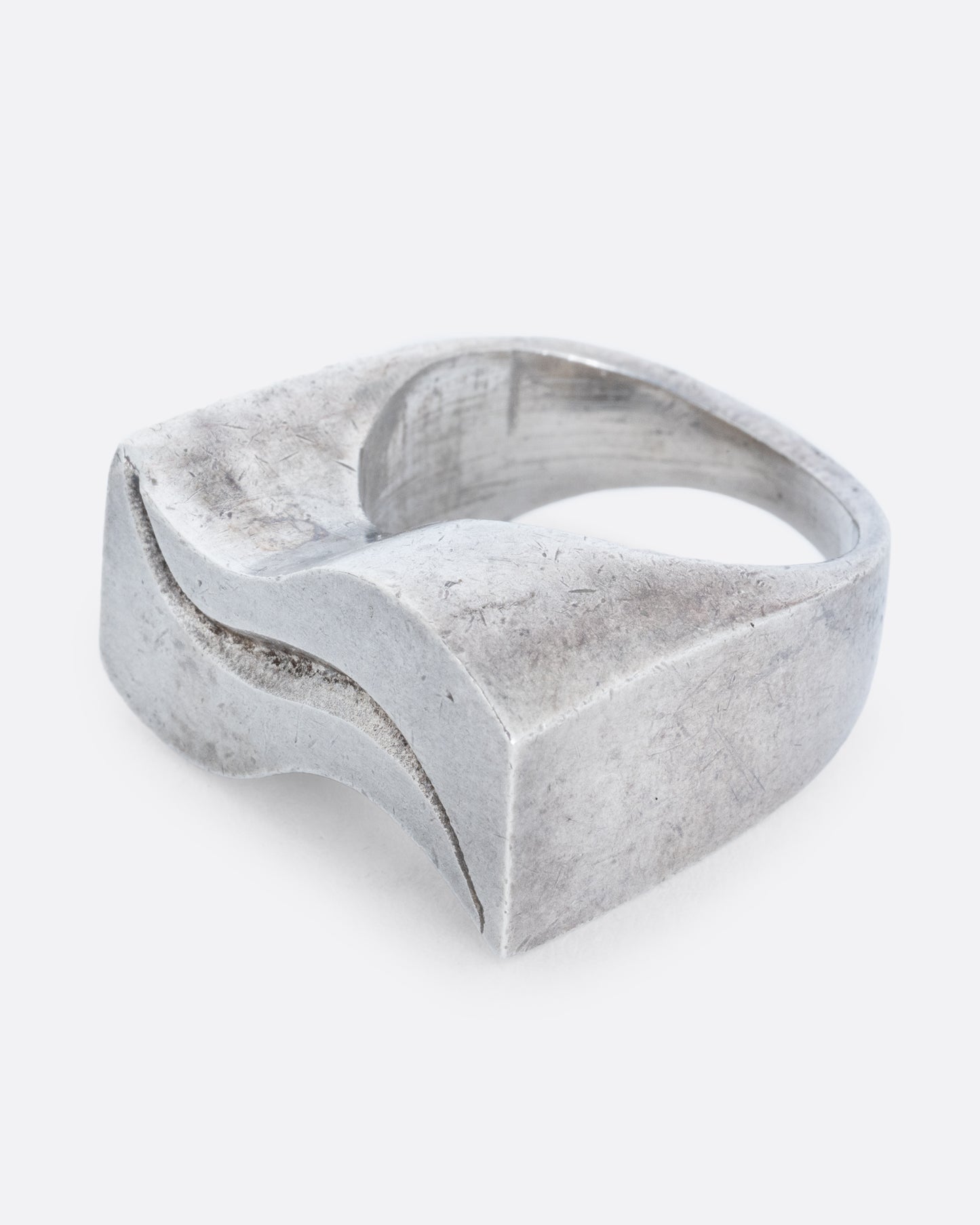 A silver ring with two waves on its face. Shown from the side.