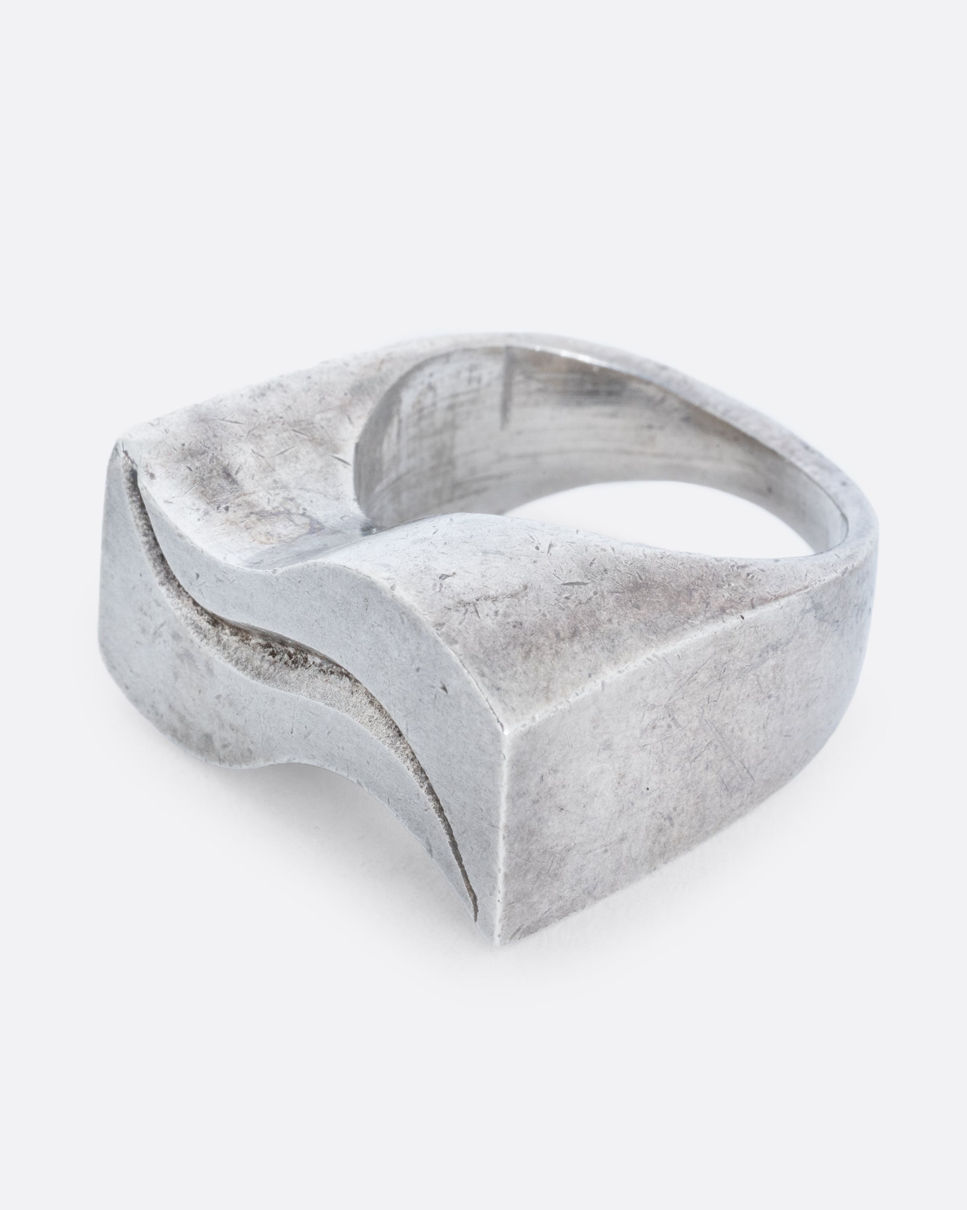 A silver ring with two waves on its face. Shown from the side.