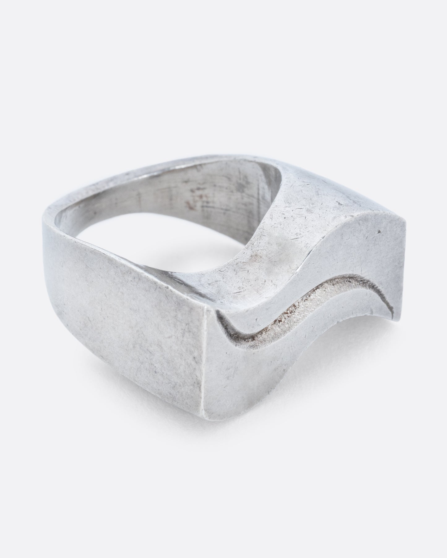 A silver ring with two waves on its face. Shown from the side.