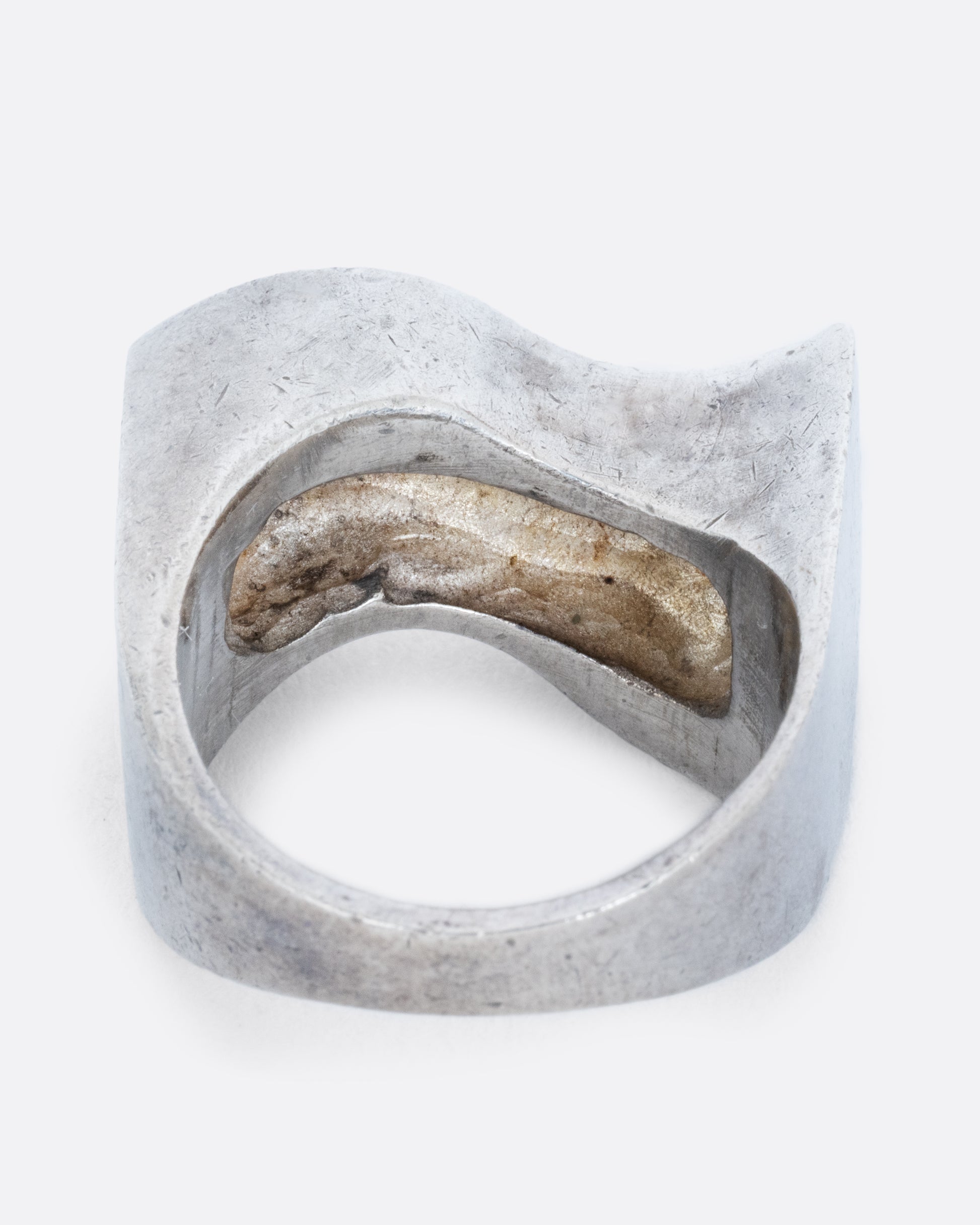 A silver ring with two waves on its face. Shown from the back.