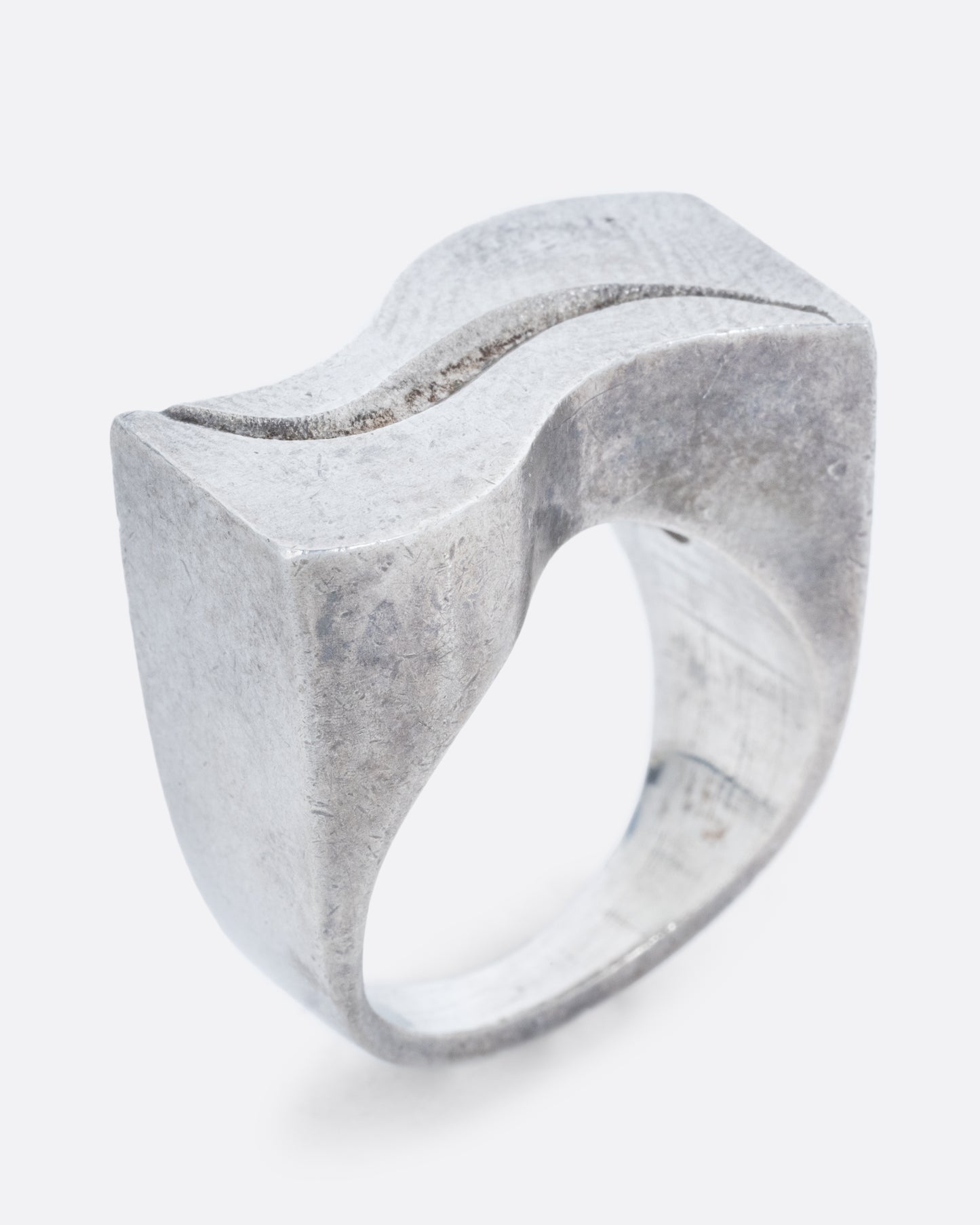 A silver ring with two waves on its face. Shown standing up from the side.