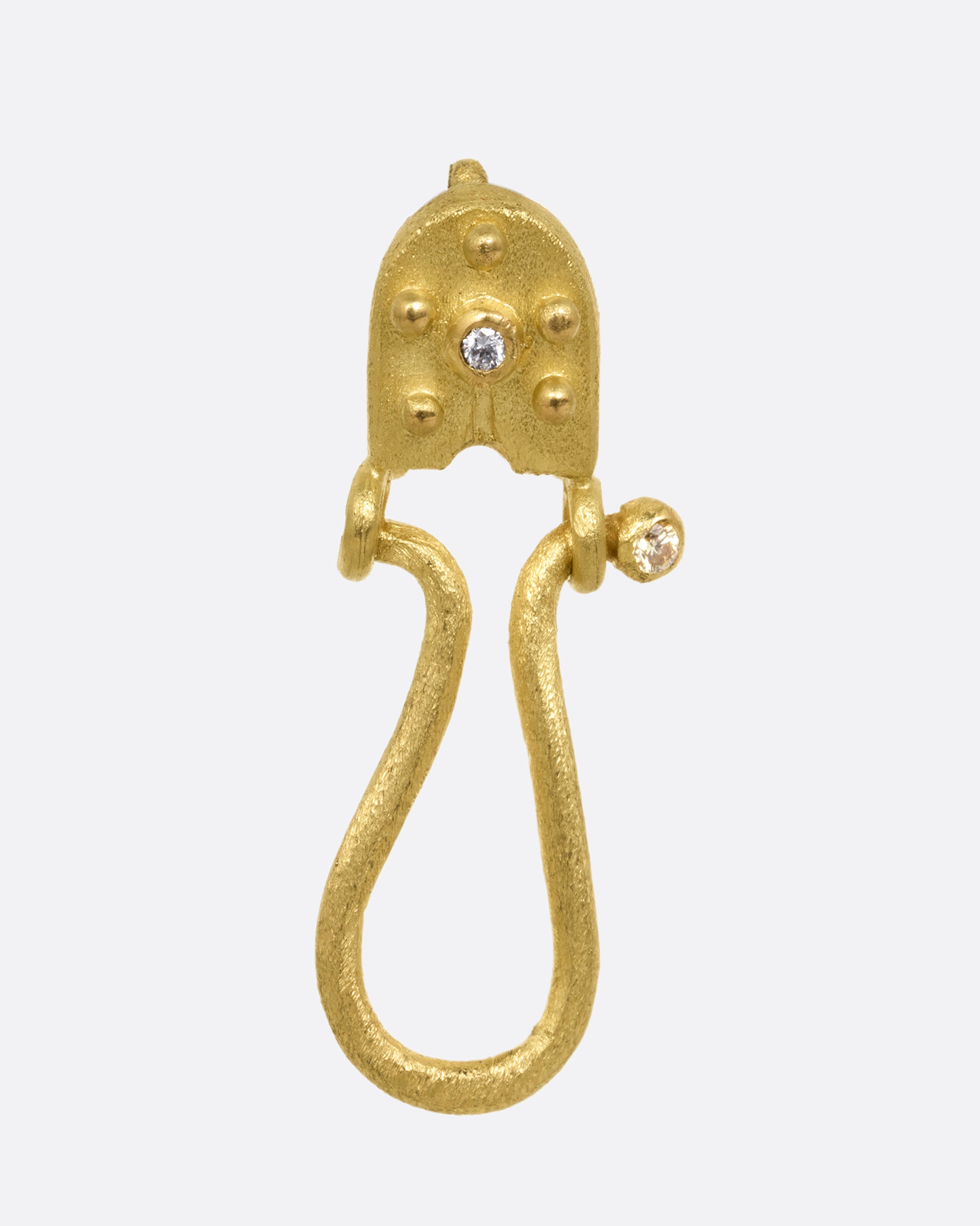 A yellow gold charm holder pendant with white diamonds at the top and at the end of the loop. Shown from the front.