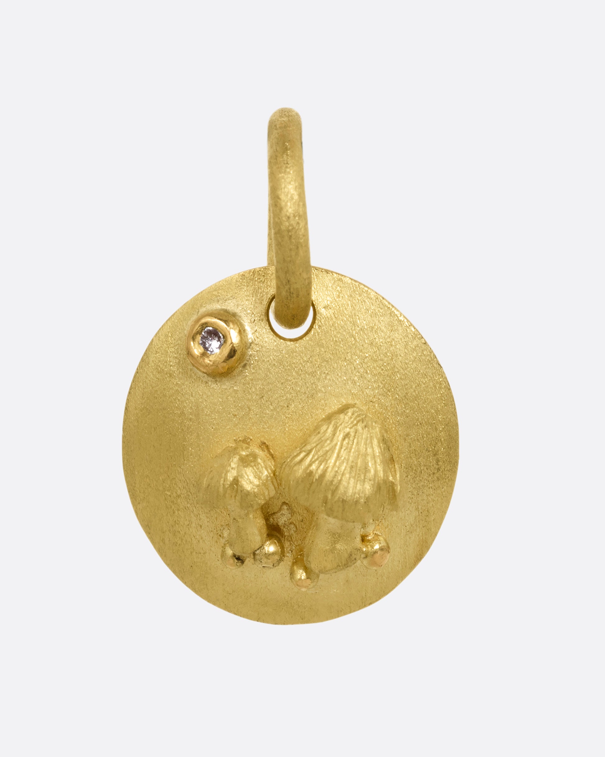 A yellow gold medallion with a diamond and mushrooms. Shown from the front.