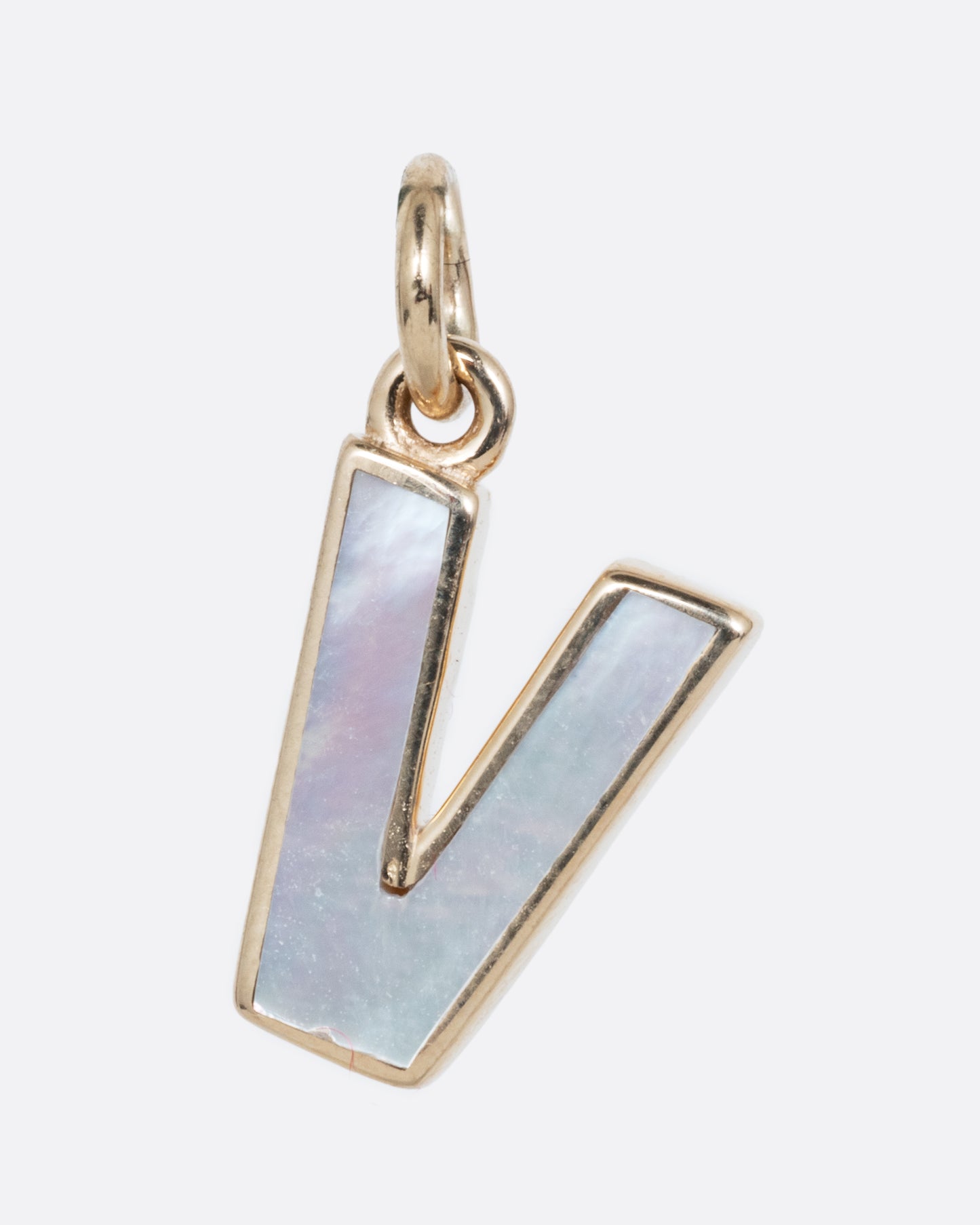 A mother of pearl V charm set in yellow gold with a yellow gold jump ring and hoop. Shown from the front.