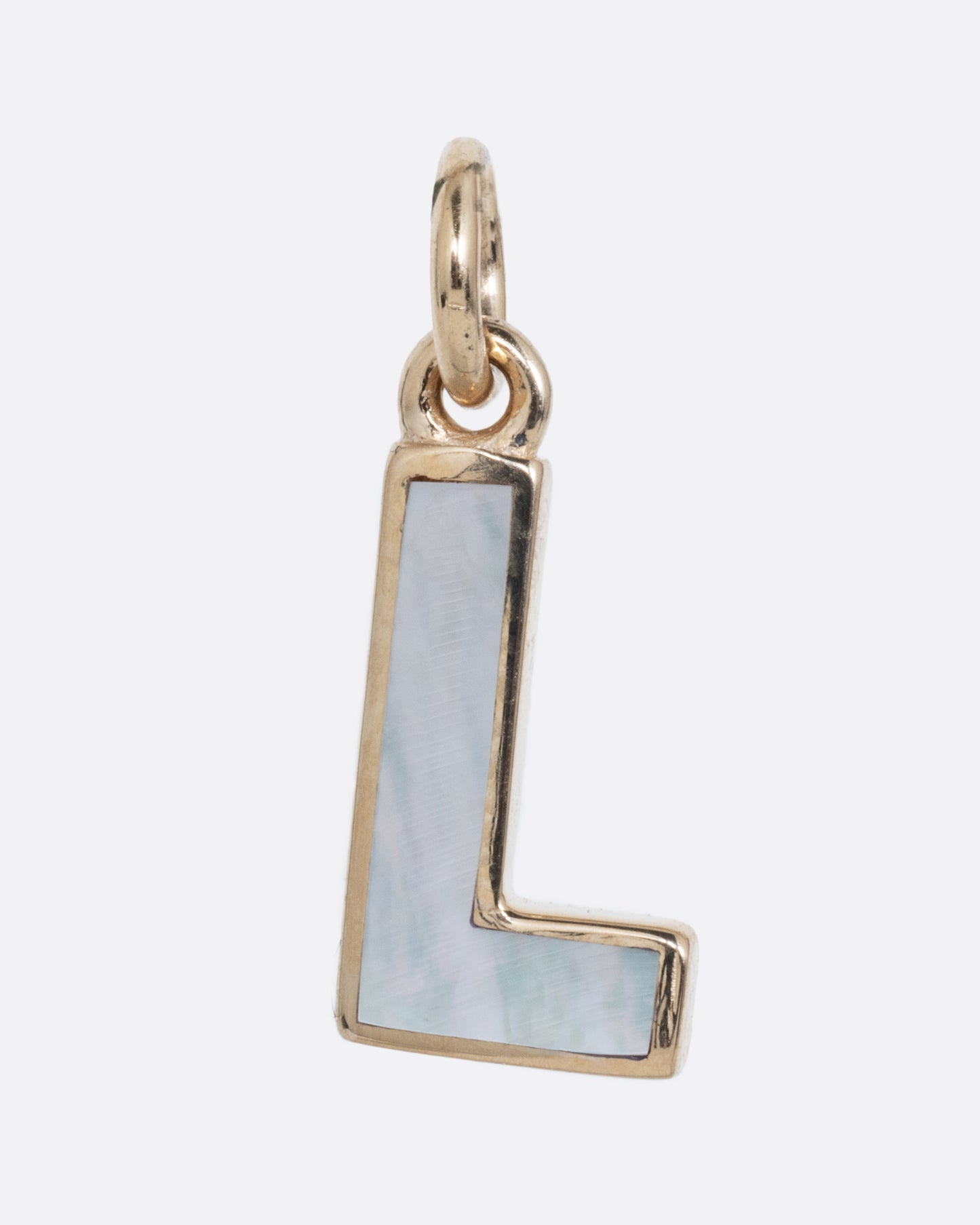 A mother of pearl inlaid L charm set in yellow gold with a yellow gold jump ring and bail. Shown from the front.