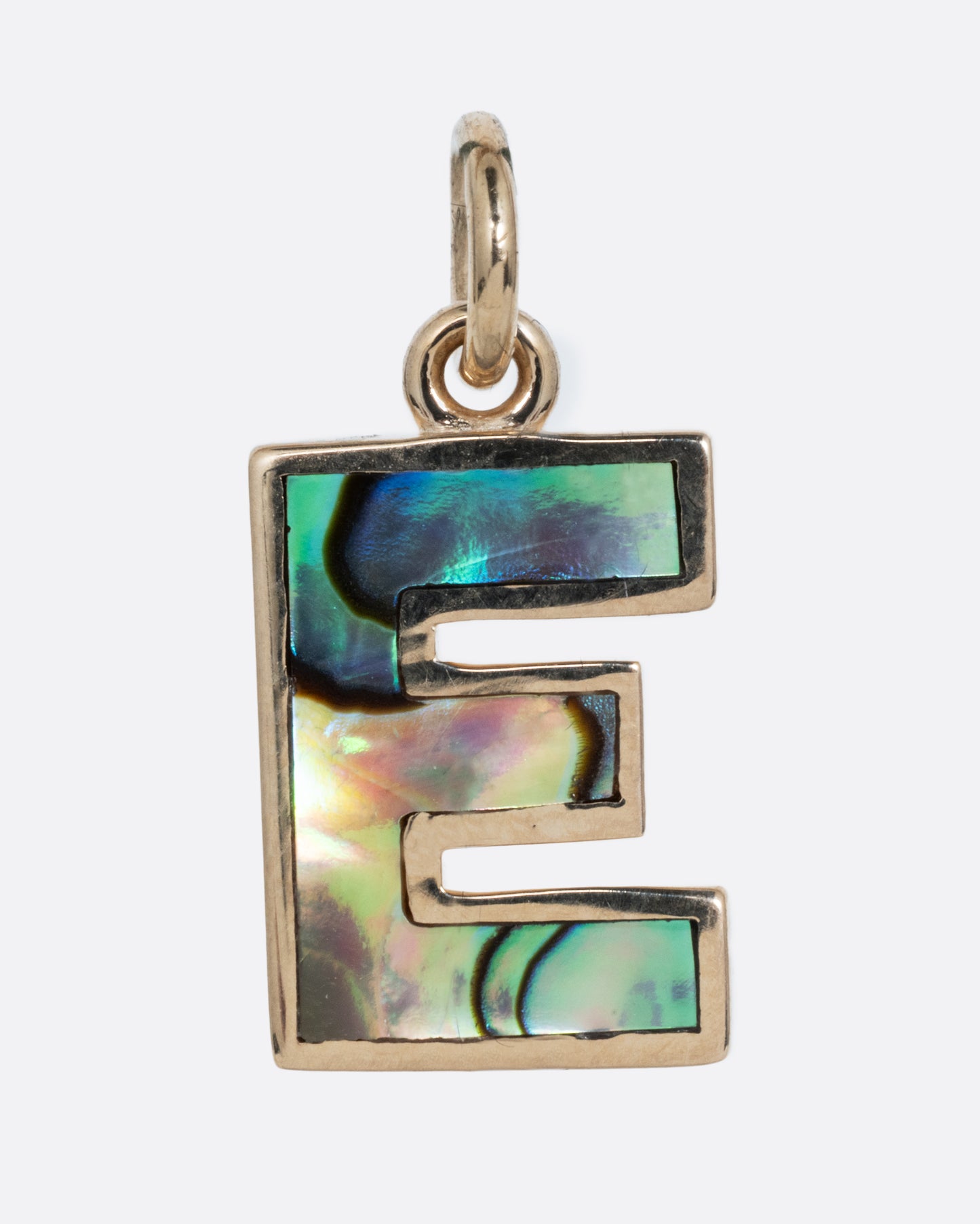 An abalone E charm set in yellow gold with a yellow gold jump ring and hoop. Shown from the front.