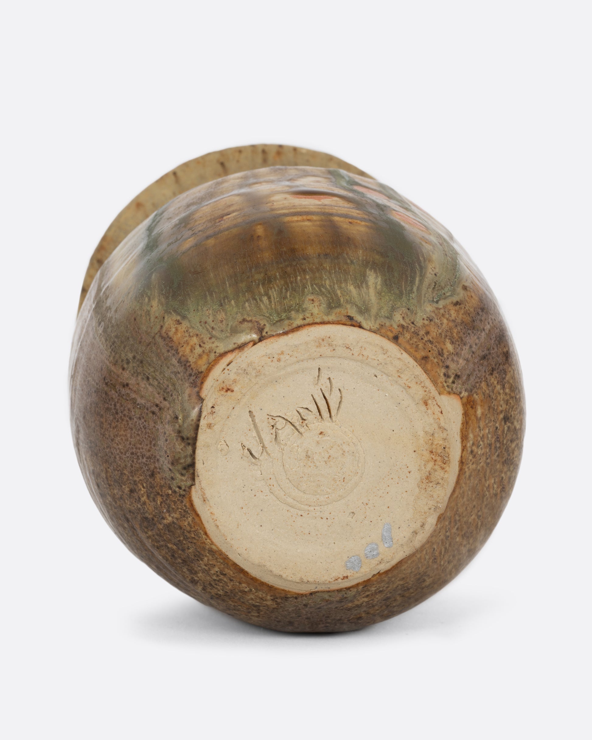 A vase with a dripped glaze of browns, greens, and orange. Shown from the bottom.