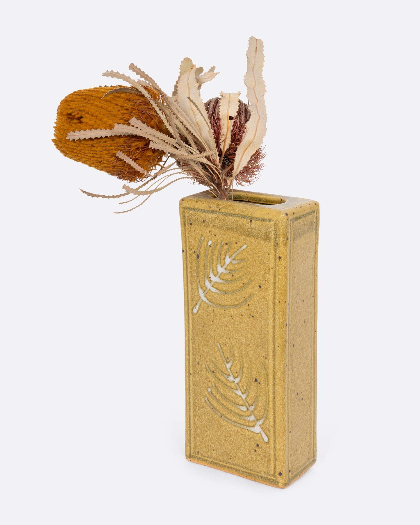 A yellow rectangular vase with botanical imagery. Shown with a flower in it diagonally from the front.