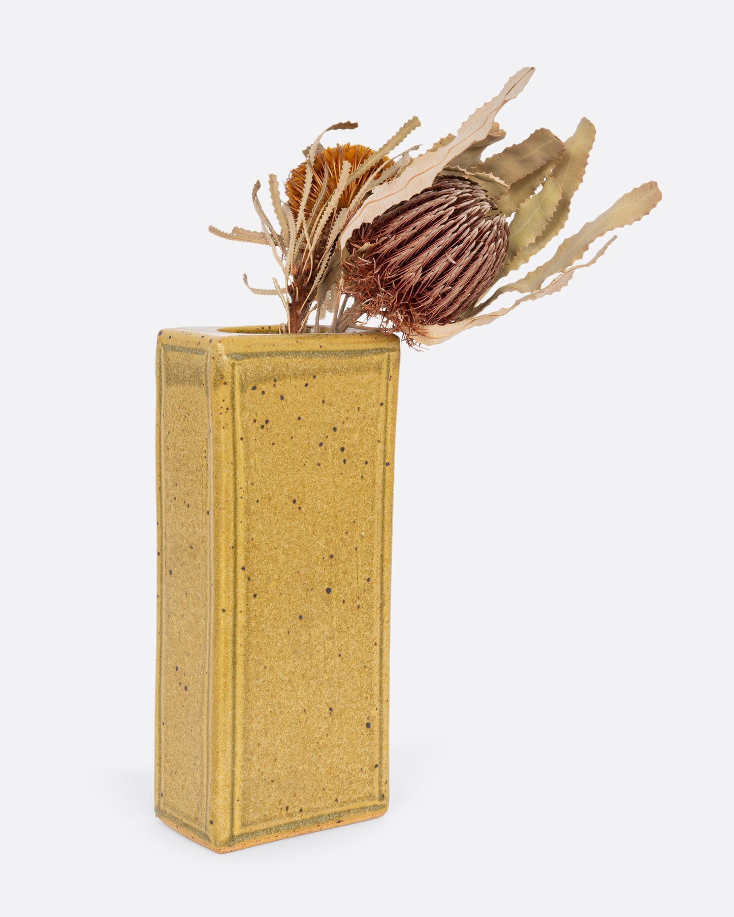 A yellow rectangular vase. Shown with a flower in it from the back.