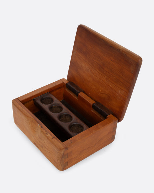 A wooden box with a hinged top and sliding ring holder. Shown open from the top.