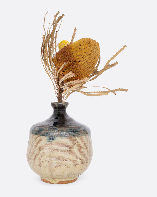 A vase with an indigo blue dipped top and ribbed texture. Shown with flowers in it from the front. 