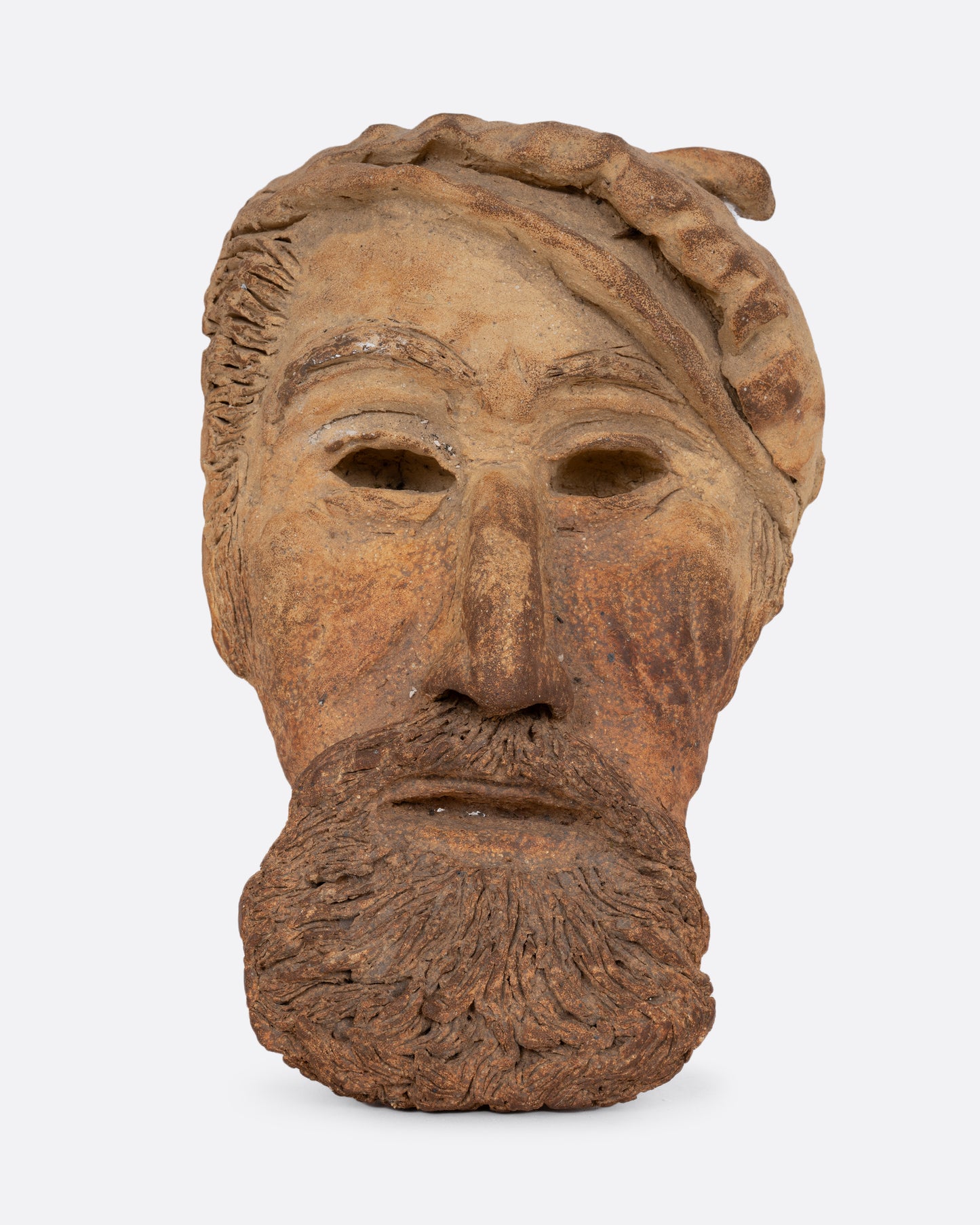 A handmade ceramic mask with a beard and hat. Shown from the front.