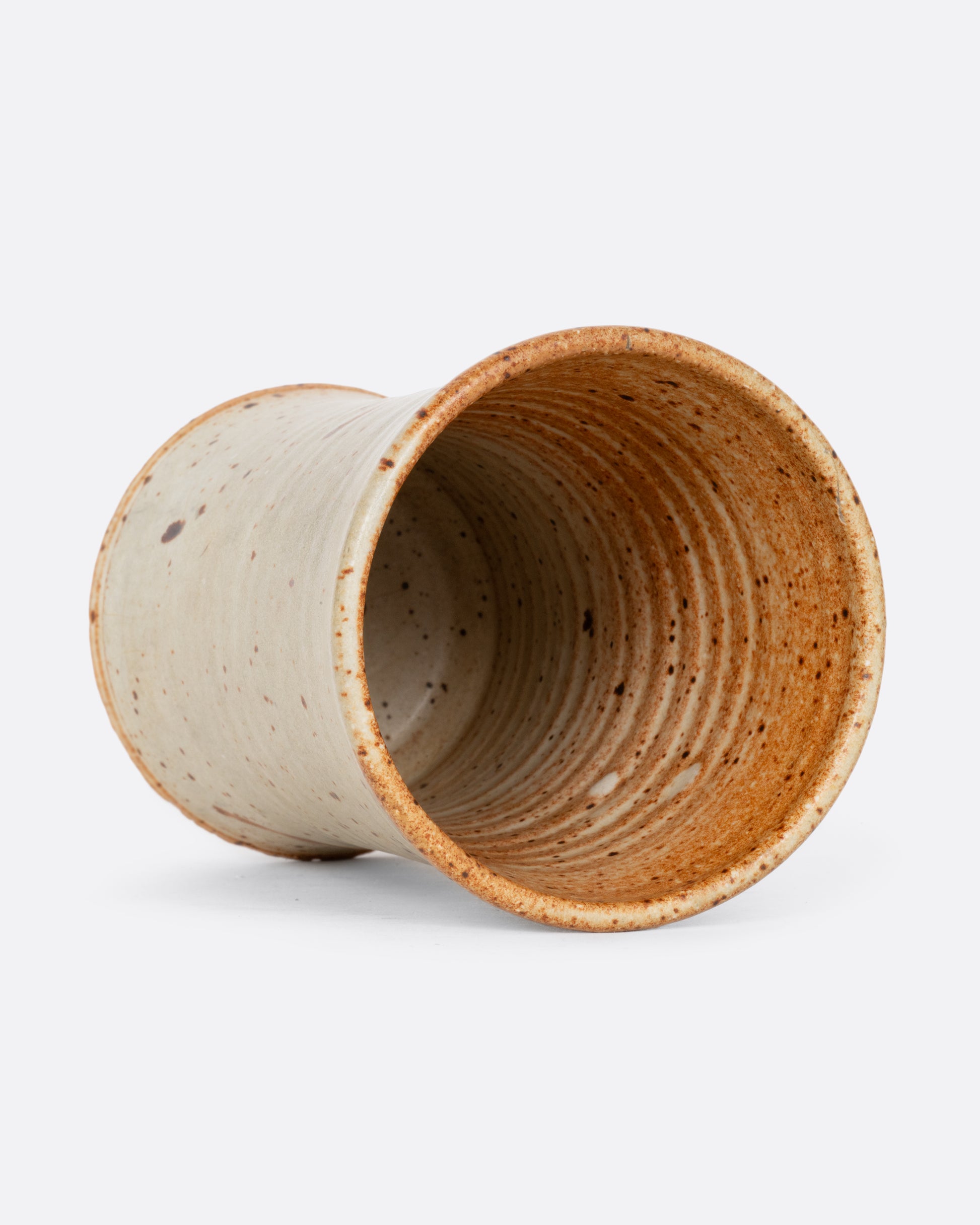 A tall speckled vessel with blue and brown splattered glaze. Shown lying flat from the top.
