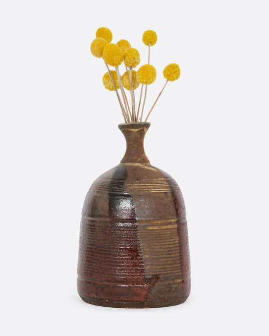 A vase with a brown split contrast glaze and ribbed texture. Shown with flowers in it from the front.