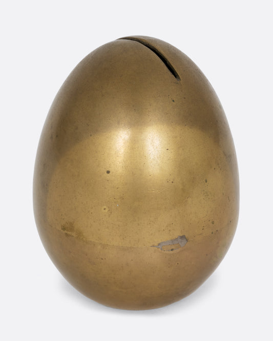  An egg shaped brass bank. Shown from the side.