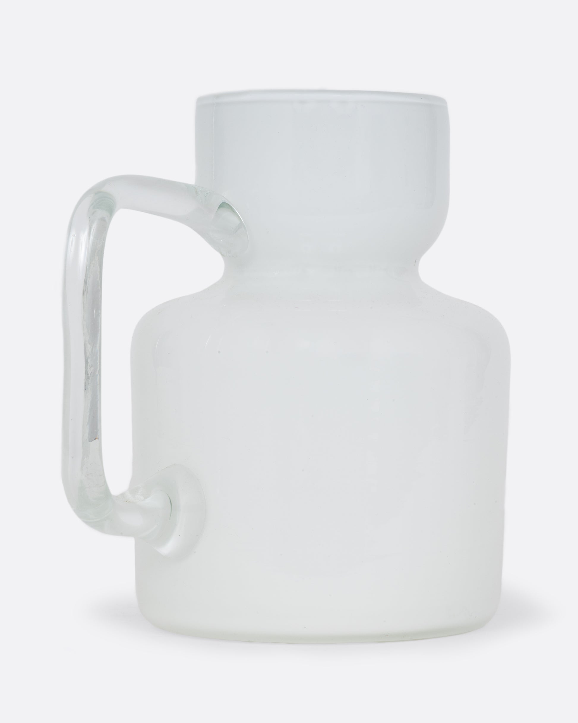 A white cased glass pitcher. Shown diagonally from the back.