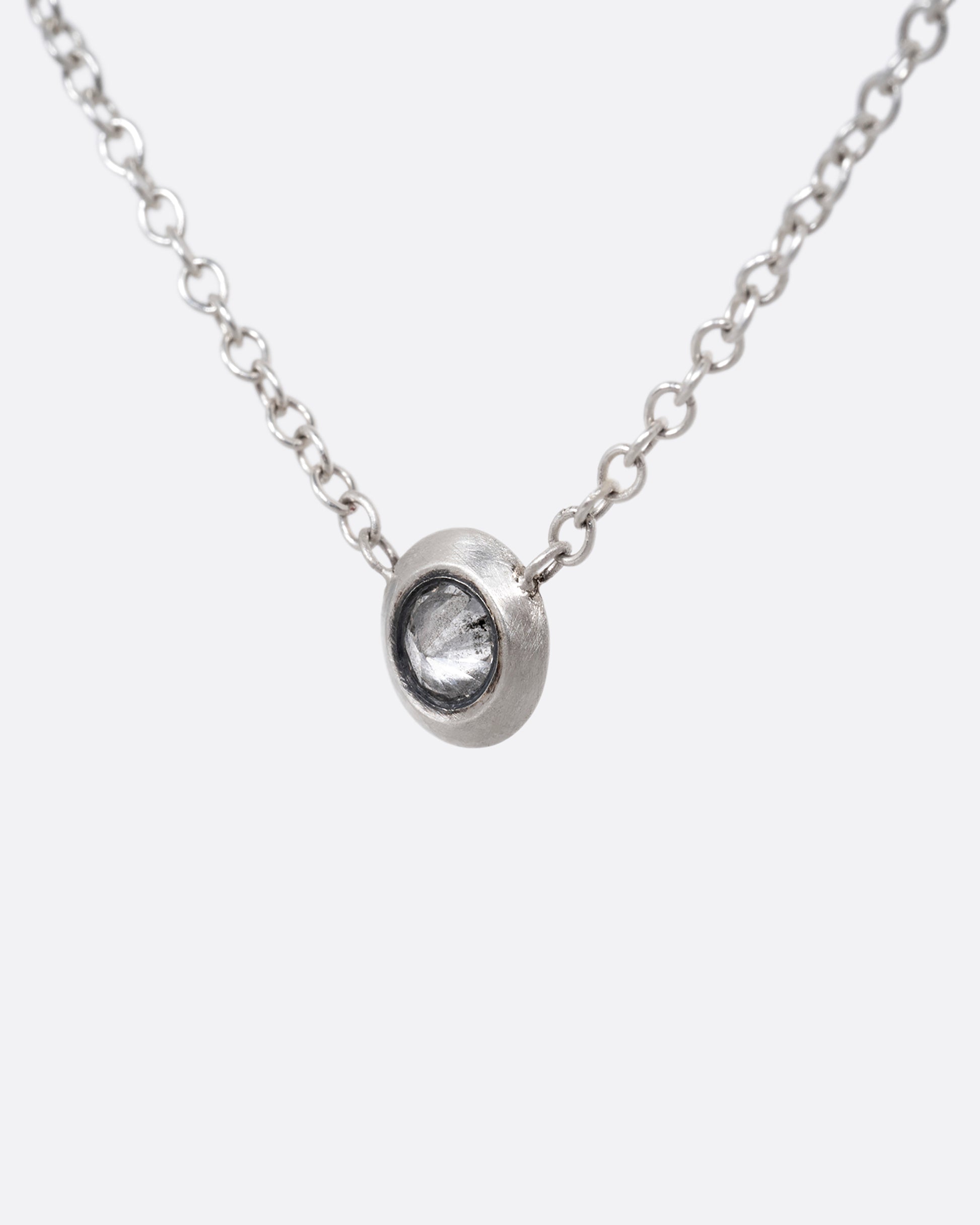 A silver cable chain necklace with a reverse set grey diamond. Shown from the front.