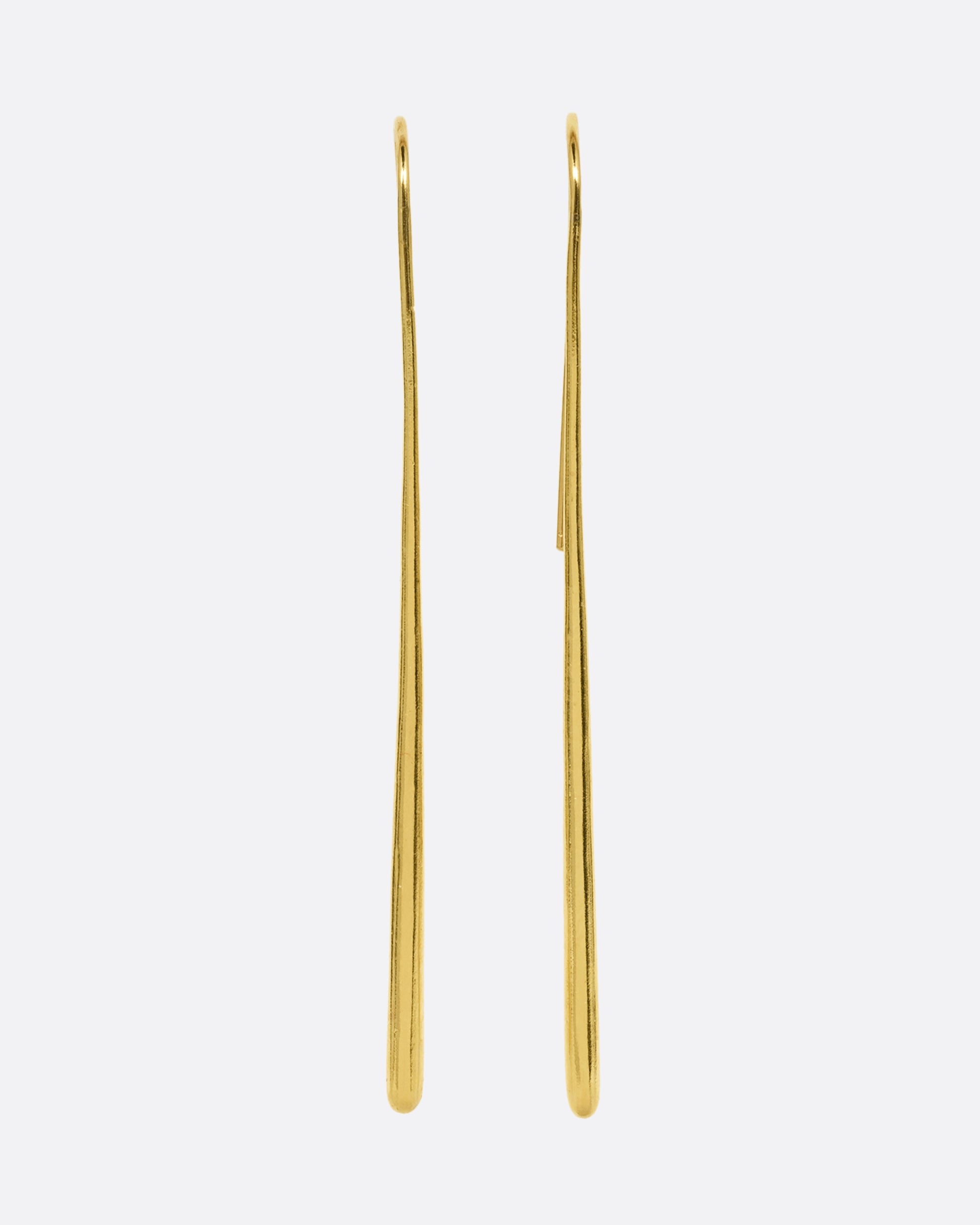 A pair of long narrow yellow gold earrings with a tapered silhouette and ear hooks. Shown from the front.