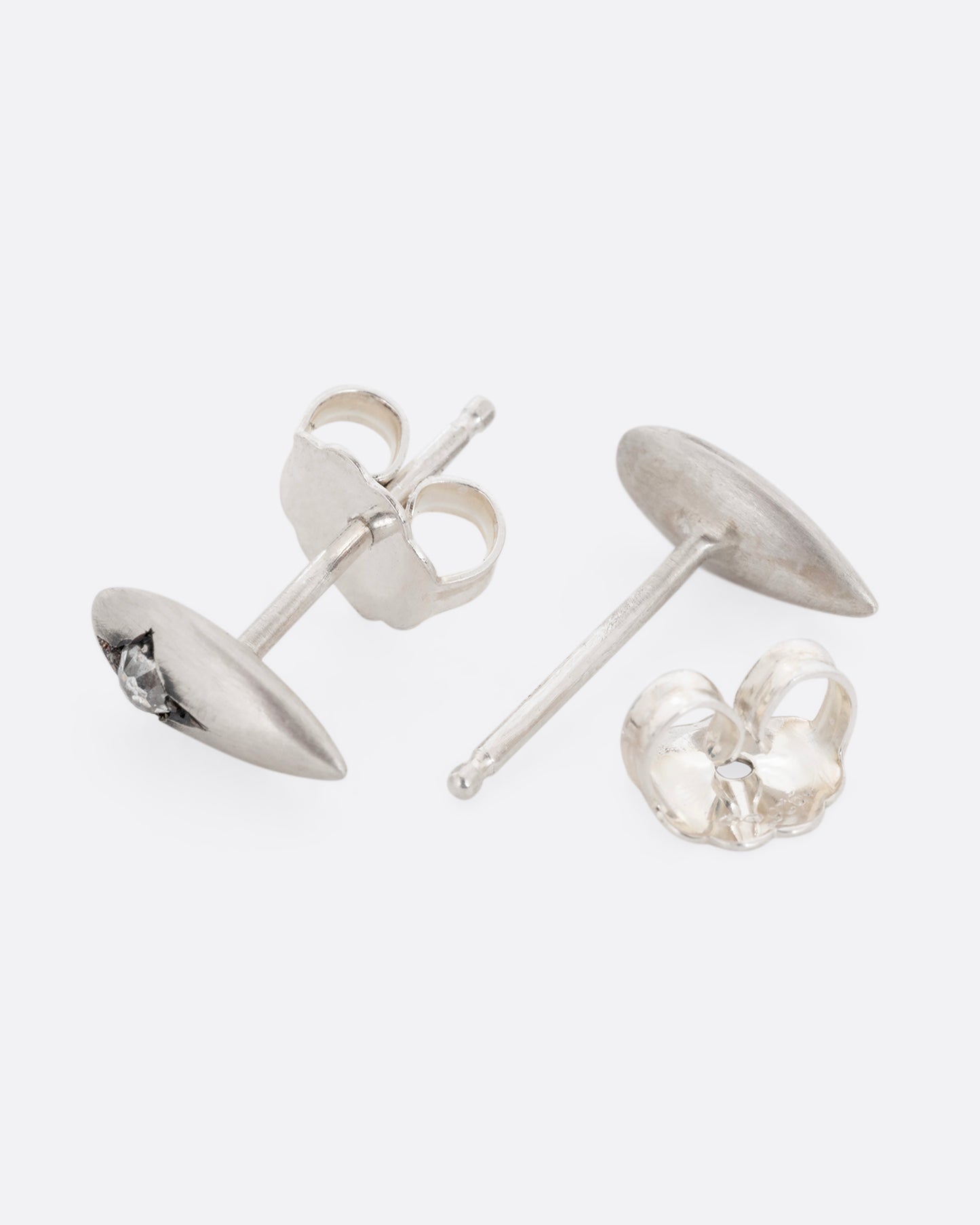 Silver teardrop shaped earrings with rose cut diamonds. One earring is shown lying flat from the front. The other earring is shown open lying flat from the back.