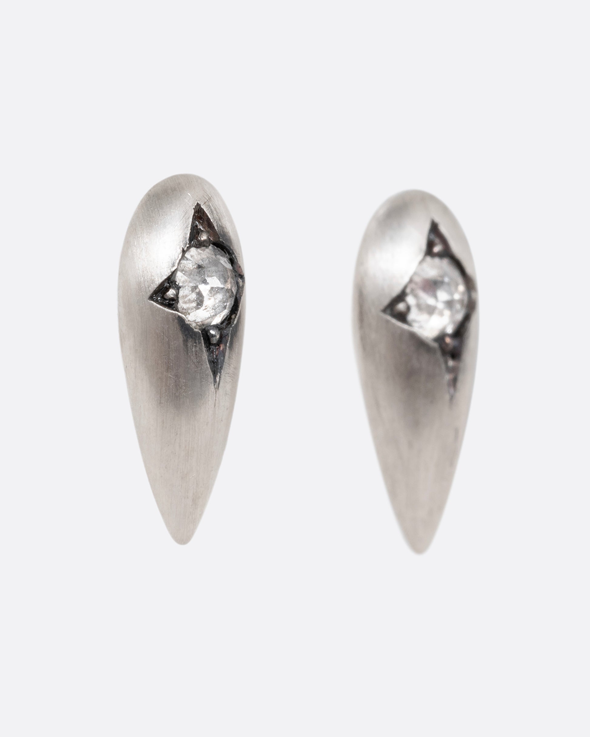 Silver teardrop shaped earrings with rose cut diamonds. Shown from the side.