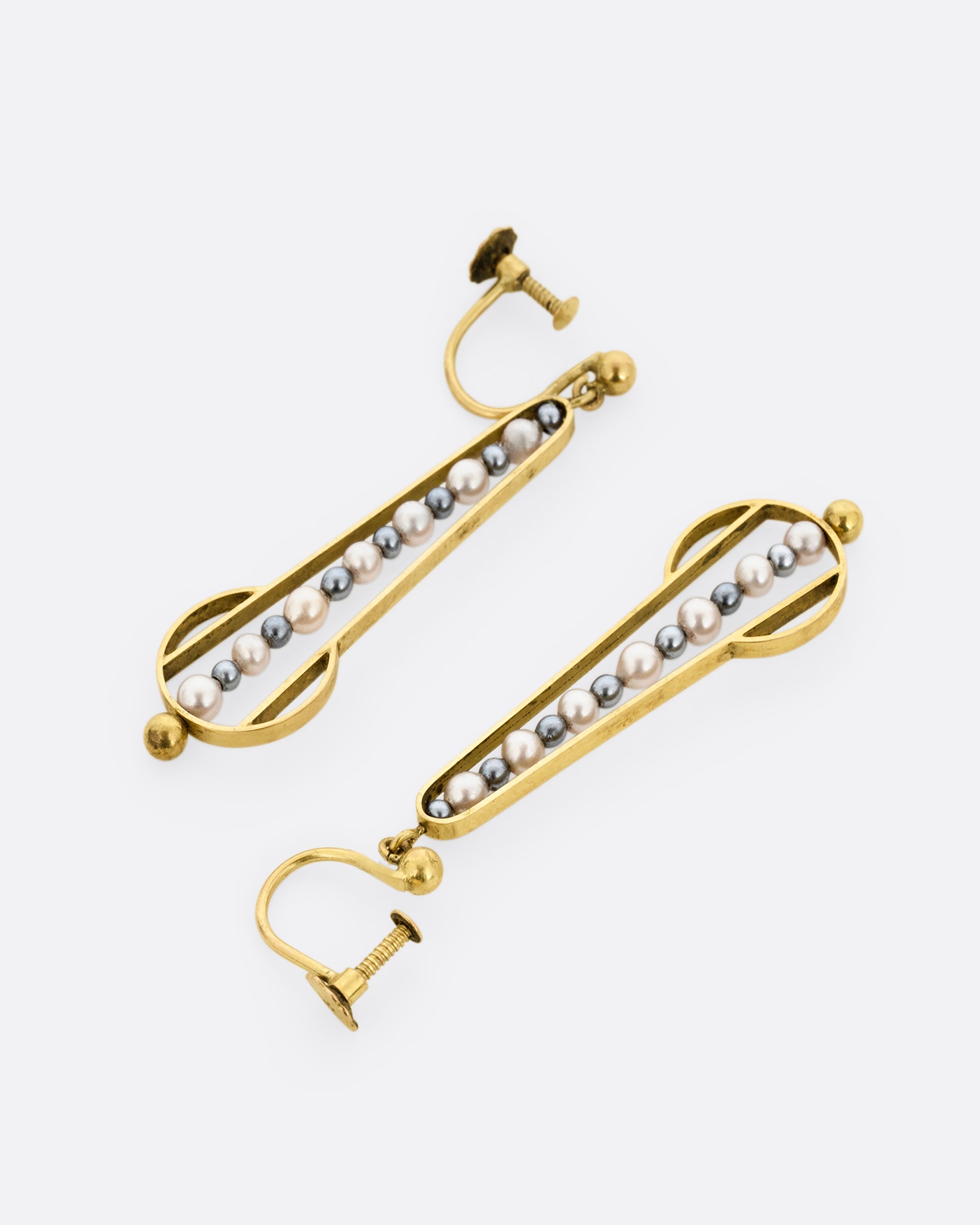Yellow gold geometric dangle earrings with screw clasps and pearls down the center. Shown lying flat; one from the front, one from the back.