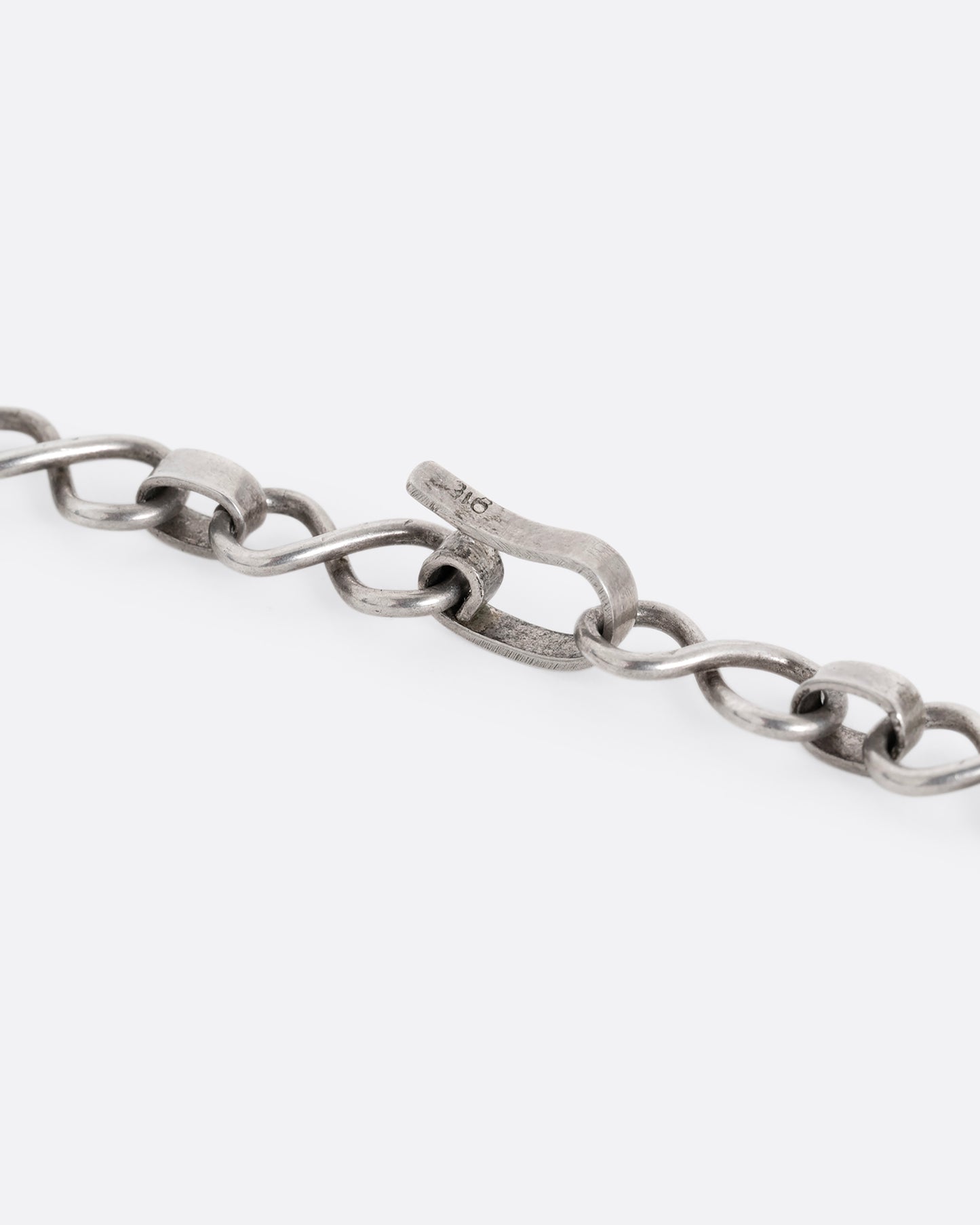A close up shot of the clasp on a silver infinity link necklace. 