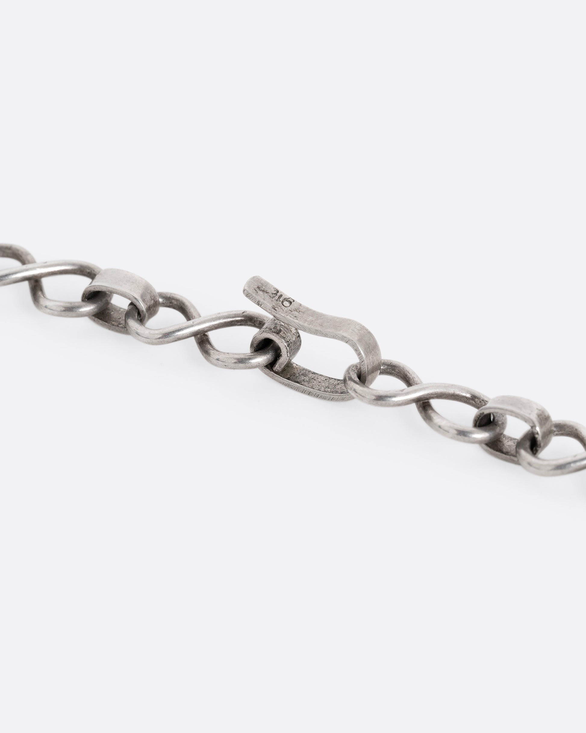 A close up shot of the clasp on a silver infinity link necklace. 