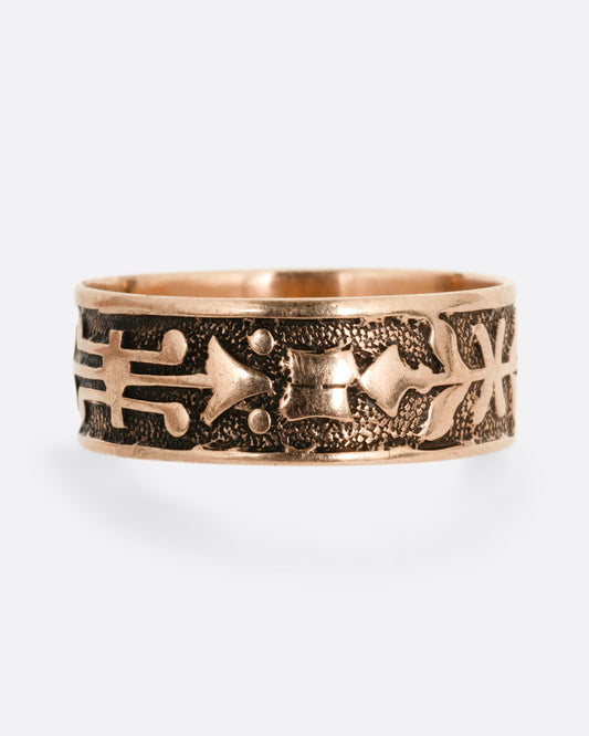 A rose gold cigar band with stamped arrow motif. Shown from the front.