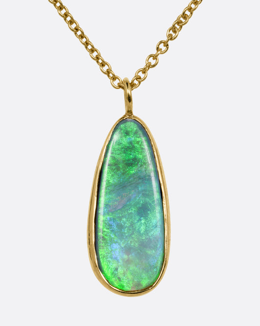 An opal pendant set in yellow gold hanging from a yellow gold cable chain. Shown from the front.