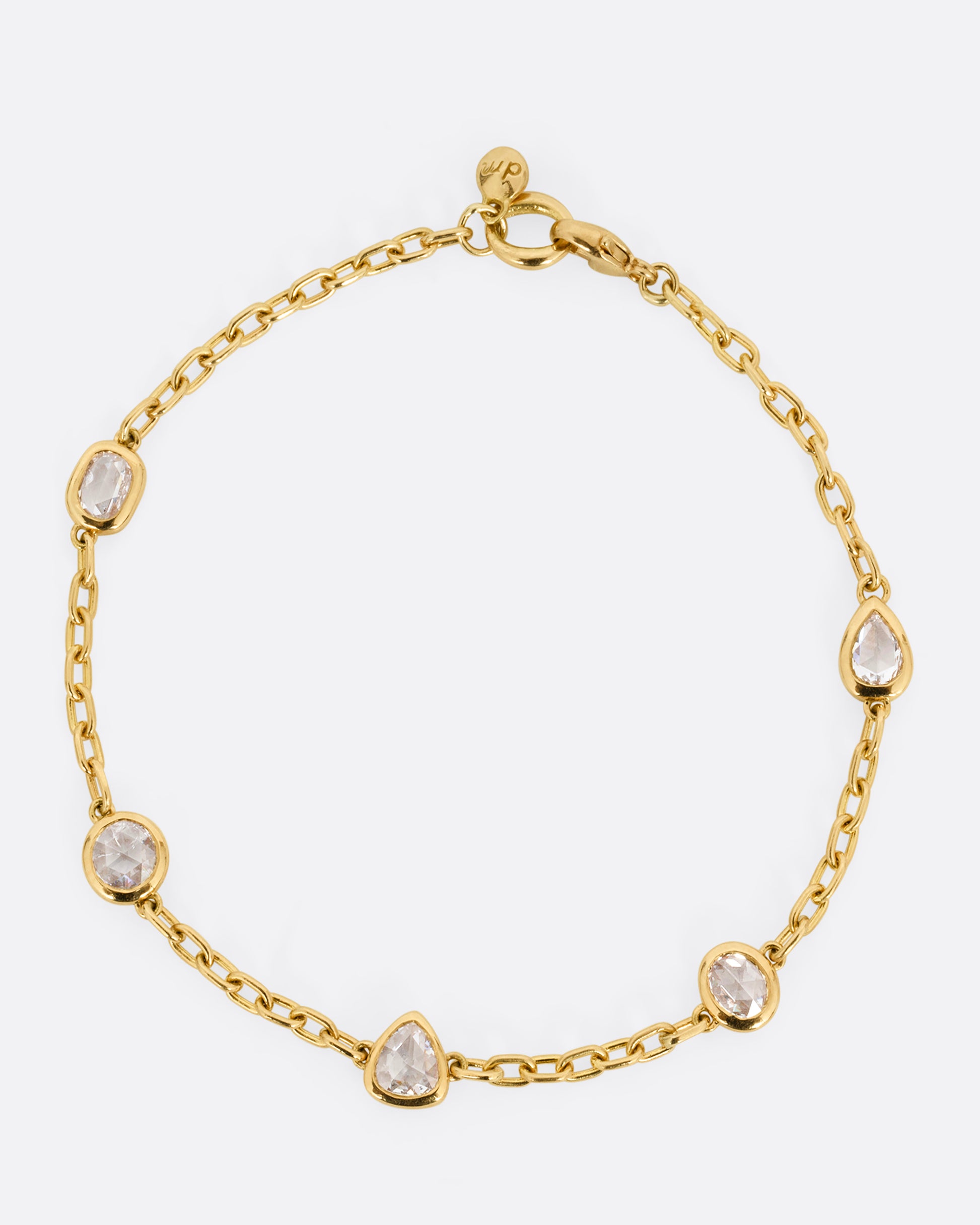 A yellow gold cable chain bracelet with five bezel set diamonds. Shown closed lying flat from the top.