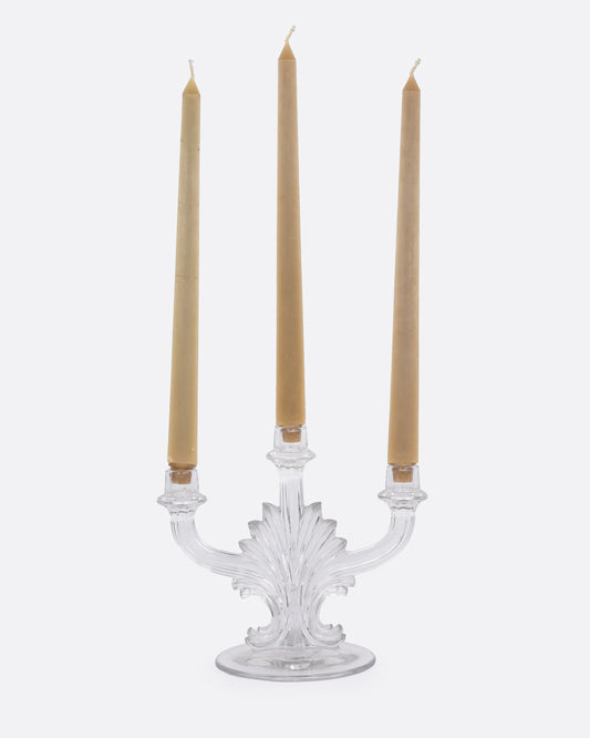 A clear glass candelabra with three holders, shown from the front with candles in each arm.