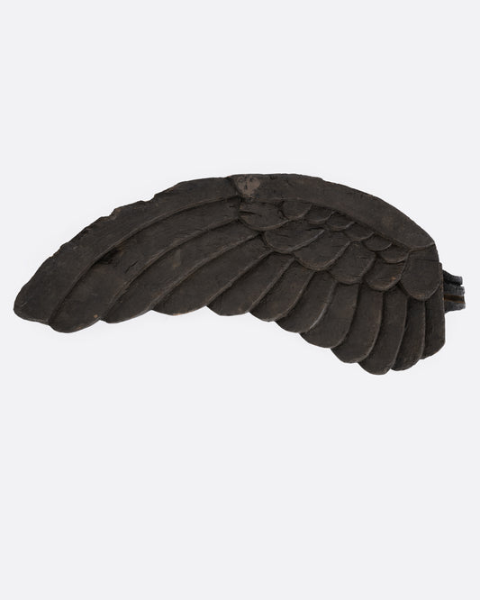 A hand carved wooden wing, shown from the front.