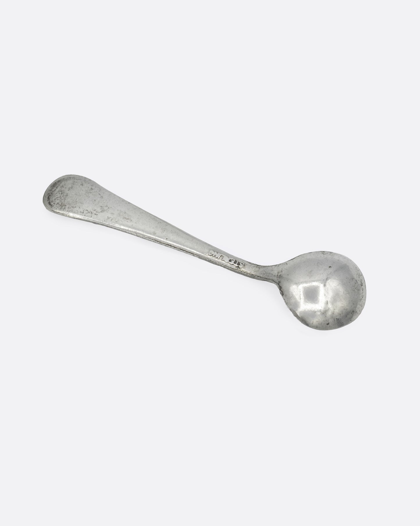 A tiny silver ladle spoon, shown from the back.