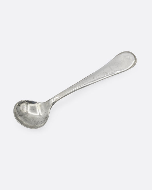 A tiny silver ladle spoon, shown from the front.