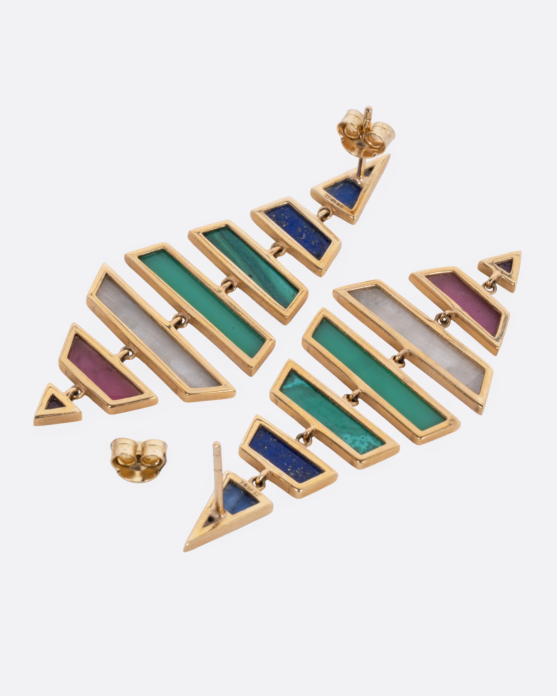 A pair of yellow gold kite shaped drop earrings with multi-colored hand cut stones, shown from the back with one earring open.