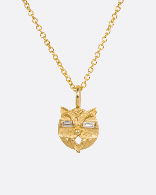 A yellow gold cable chain necklace with a cat head shaped pendant with baguette diamond eyes, shown from the front.